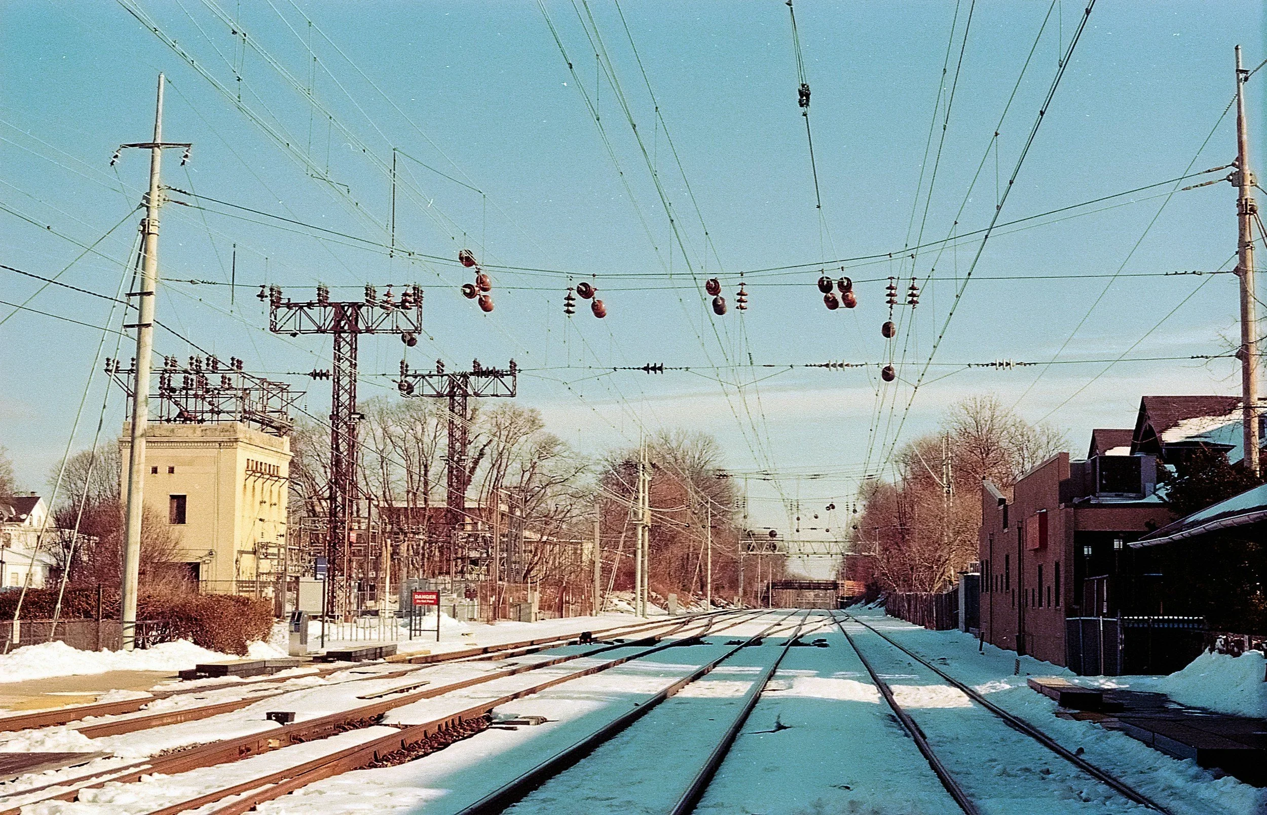 Snow-covered train tracks stretching into the horizon under overhead power lines, symbolizing the journey of moving forward, getting unstuck, and finding direction during a long Pennsylvania winter, as discussed by trauma therapist Mariah J. Zur.