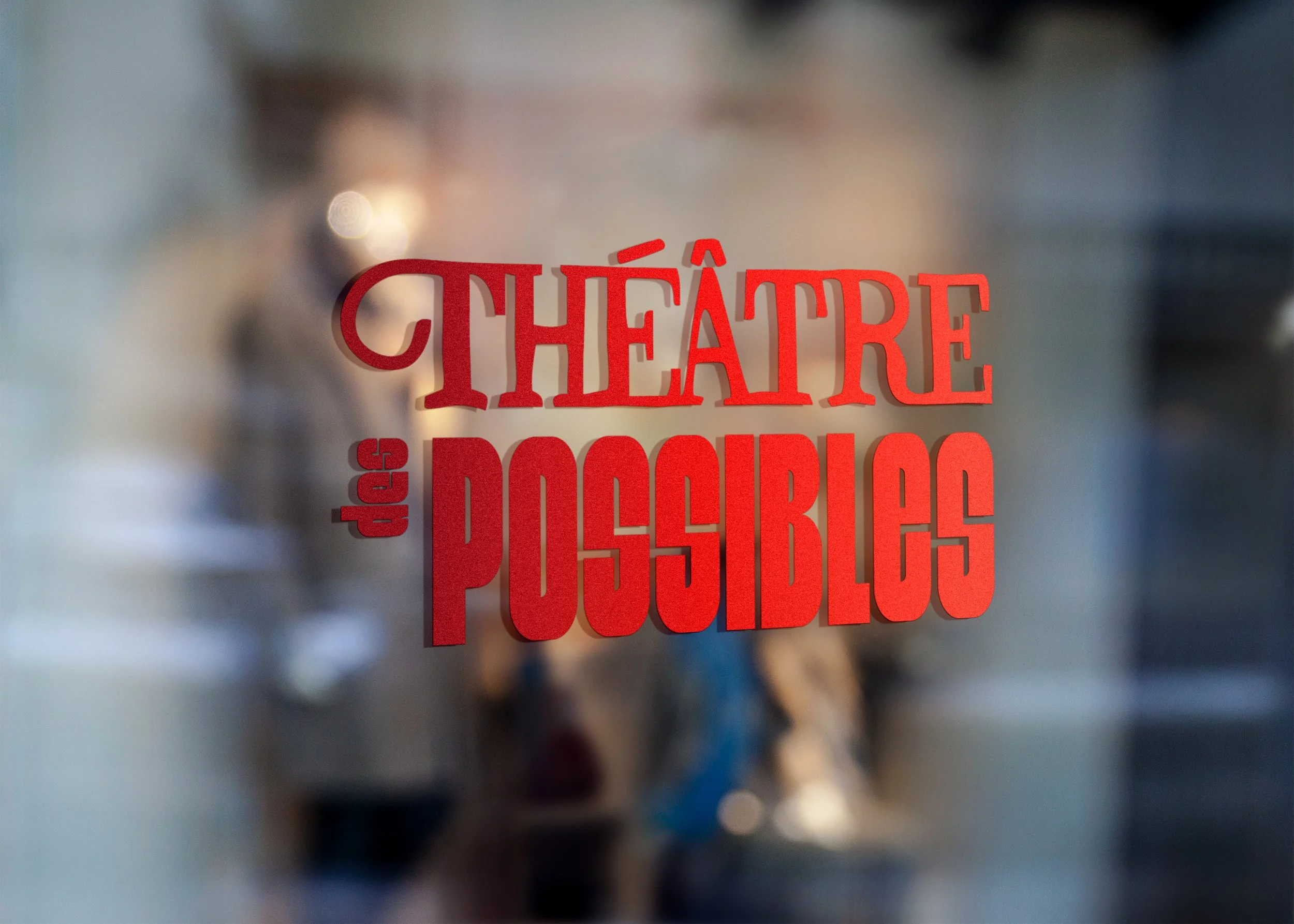 Une porte en verre avec le texte rouge 'Théâtre des Possibles' écrit dessus.