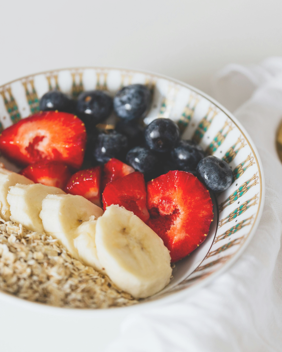 Bowl of sliced strawberries, blueberries, banana slices, and granola.