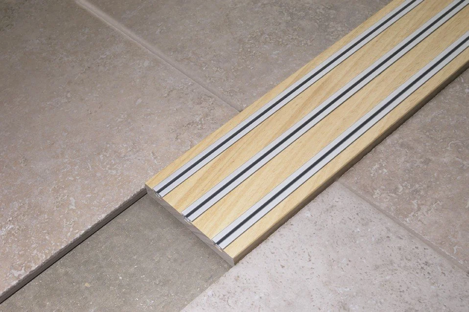 Wooden tile edge transition strip with metal strips for flooring transition.
