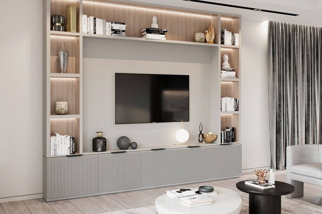 Modern living room with a wall-mounted TV, built-in shelves with books and decorative items, a white ceiling, gray patterned curtains, and a light-colored wooden floor.