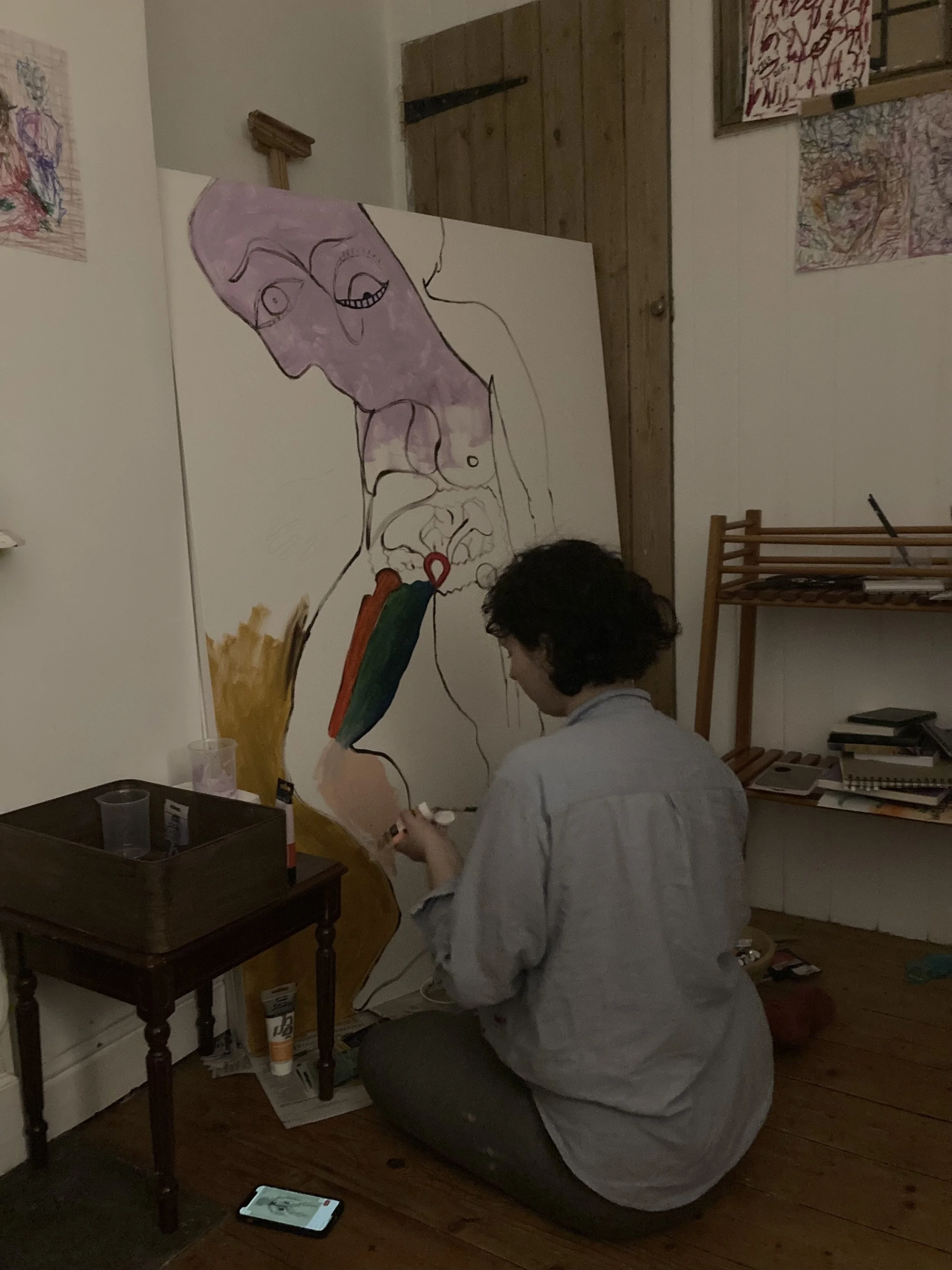 miriam schechter painting a large abstract artwork with colourful and line art details in a room with wooden floors and a small table