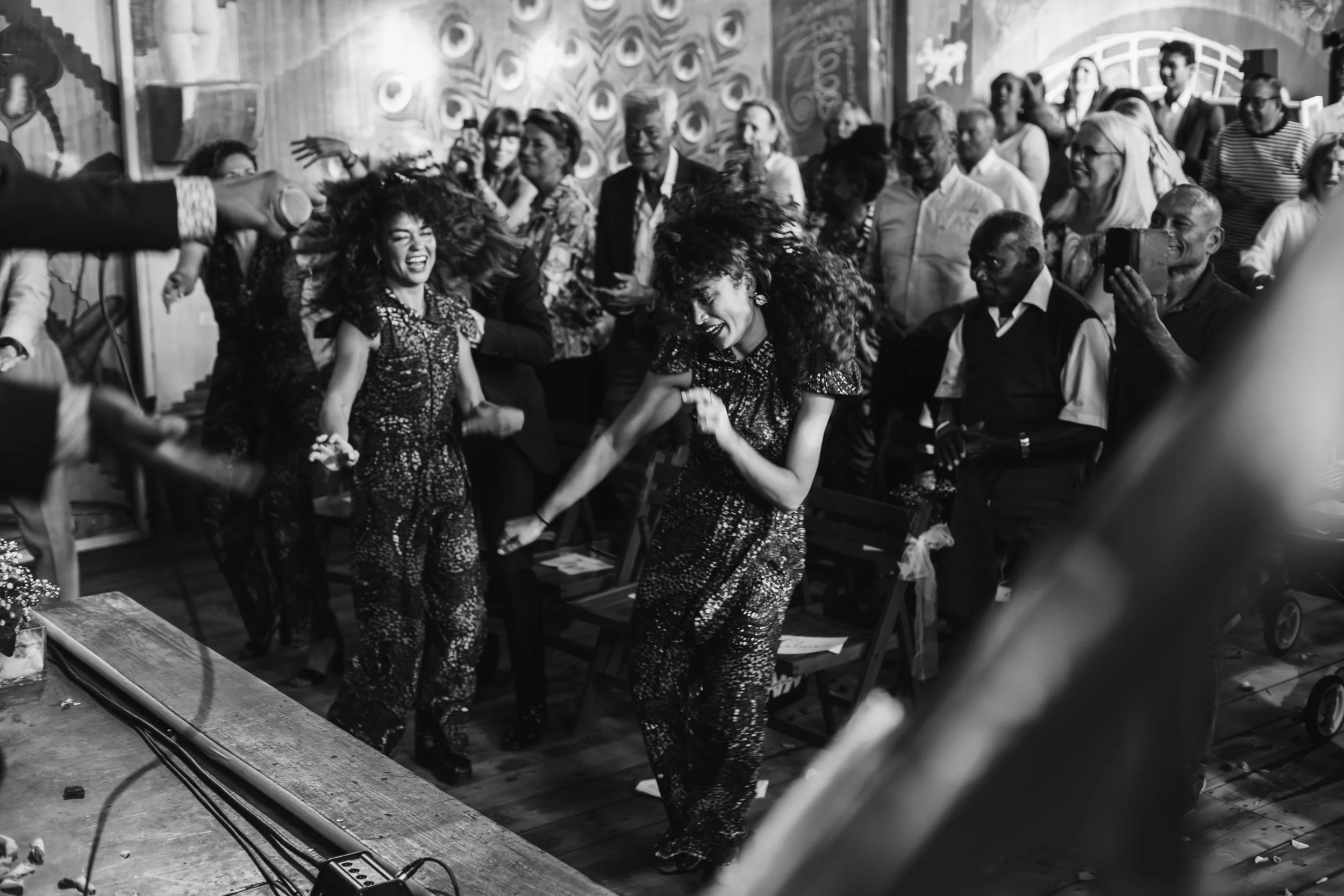 People dancing and enjoying music at a lively social event, with a crowd of spectators watching.