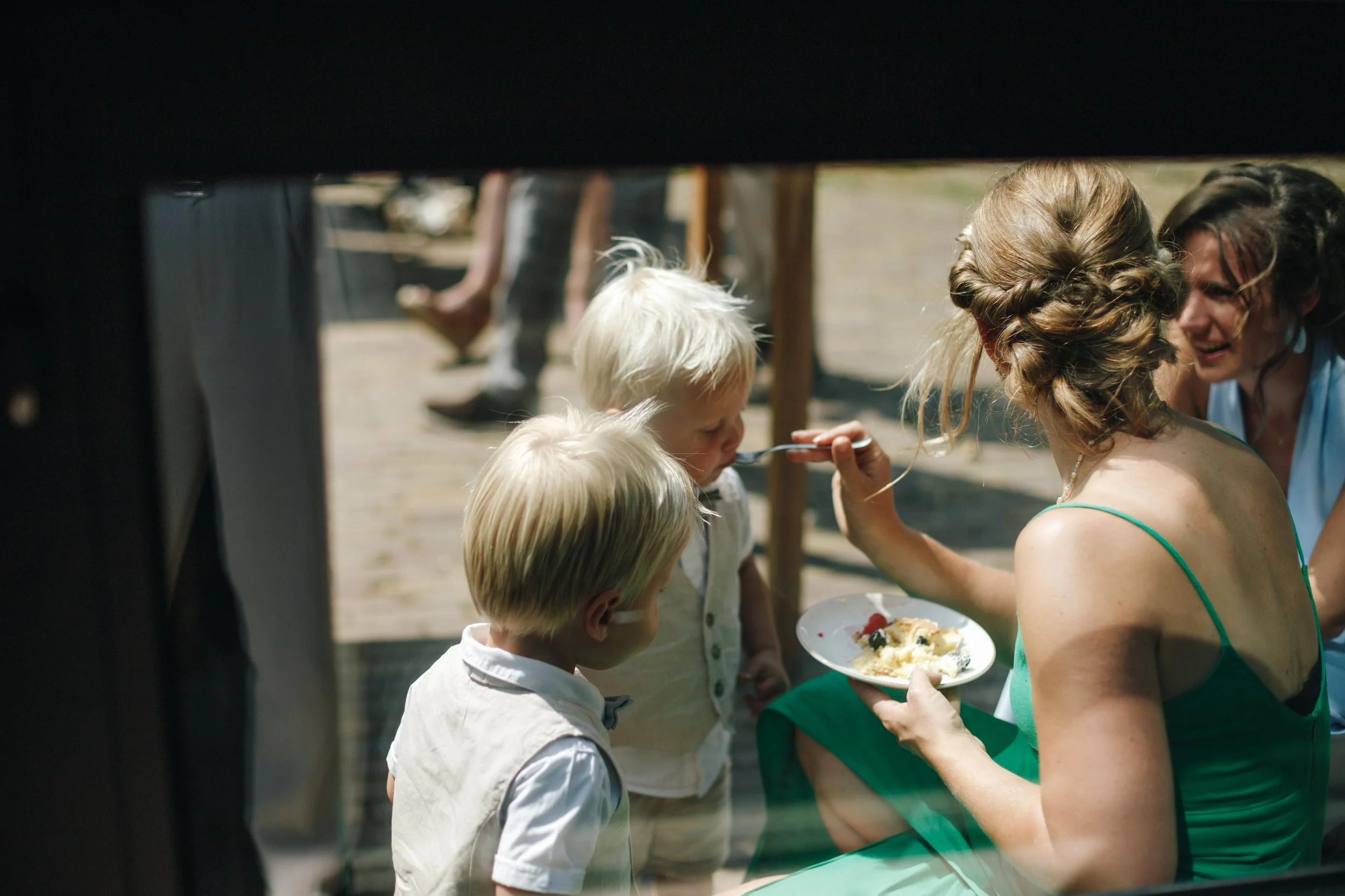 Woman feeding two children cake at outdoor gathering