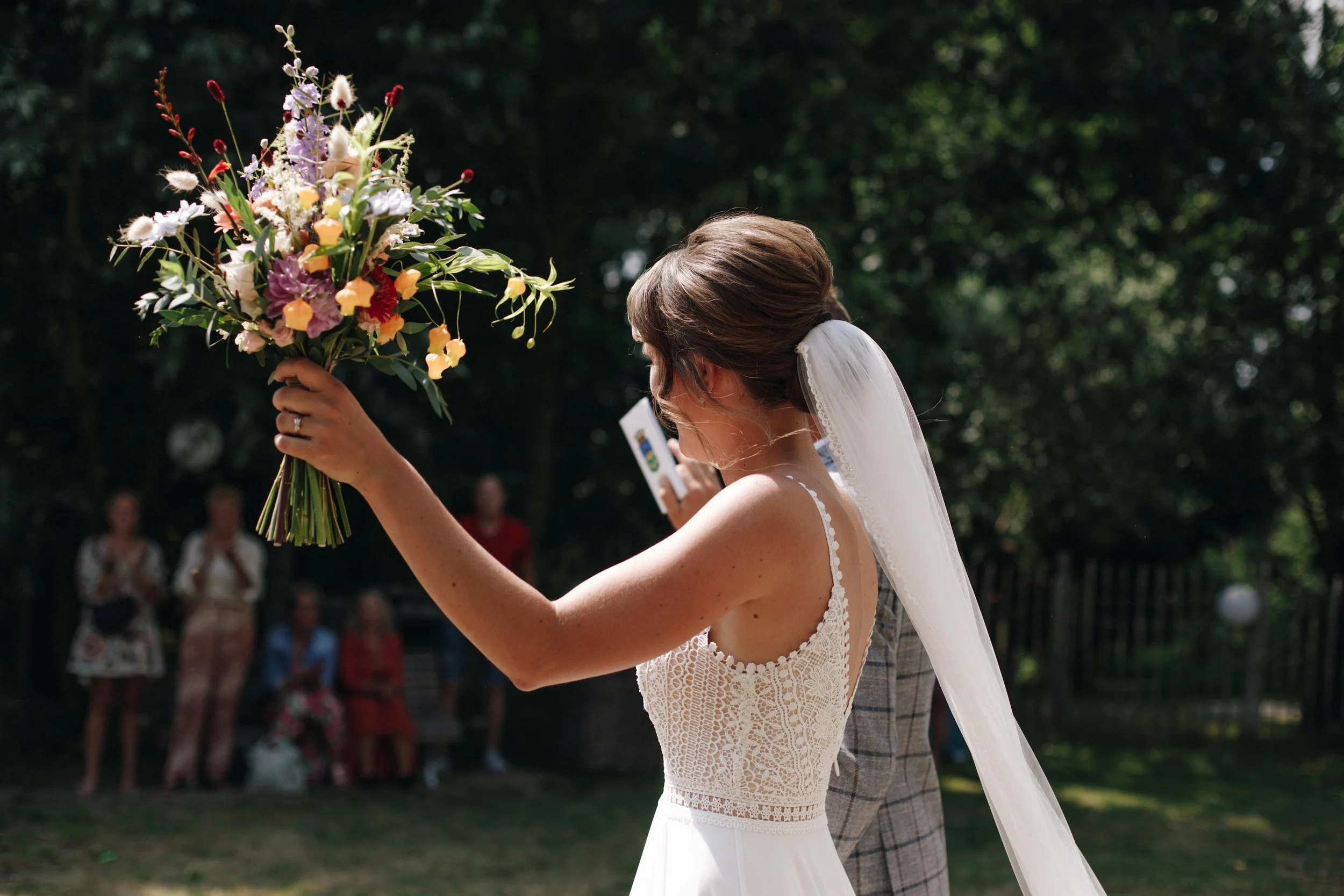 Bride holding a bouquet of flowers during an outdoor wedding ceremony.