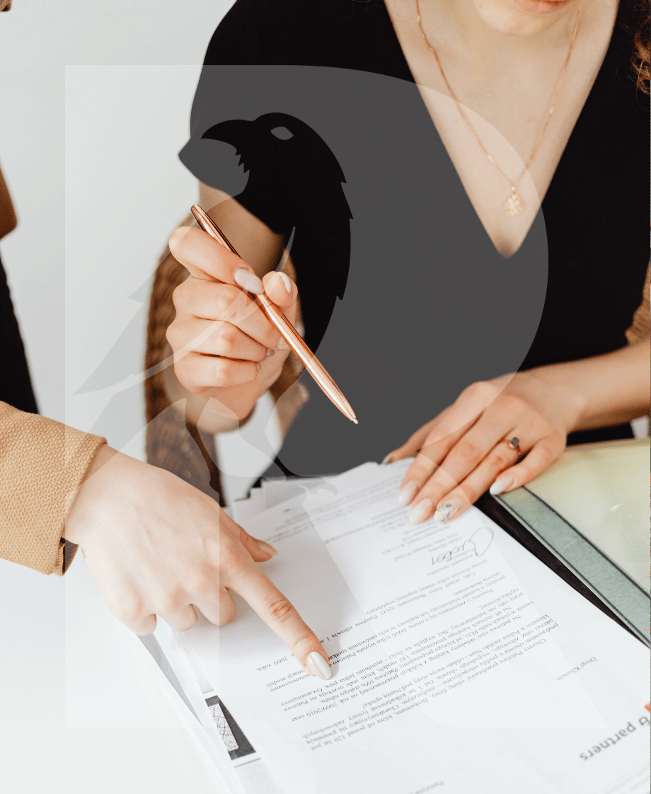 Zwei Frauen unterschreiben und besprechen einen Vertrag auf einem Tisch, eine Frau zeigt auf das Dokument, eine andere hält einen Stift.