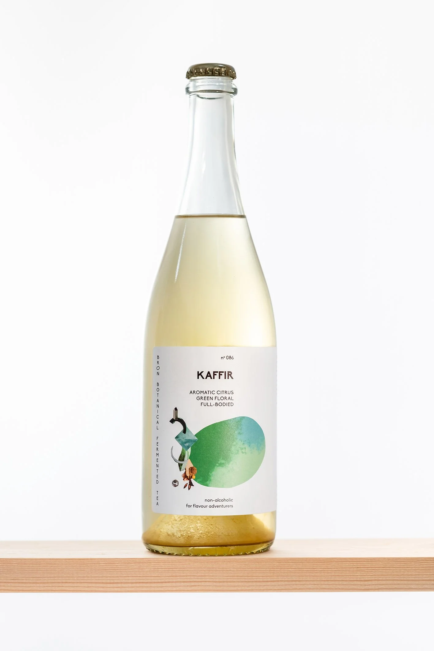 Flesje met drankje met witte label en groene illustratie, op houten vlak tegen witte achtergrond.