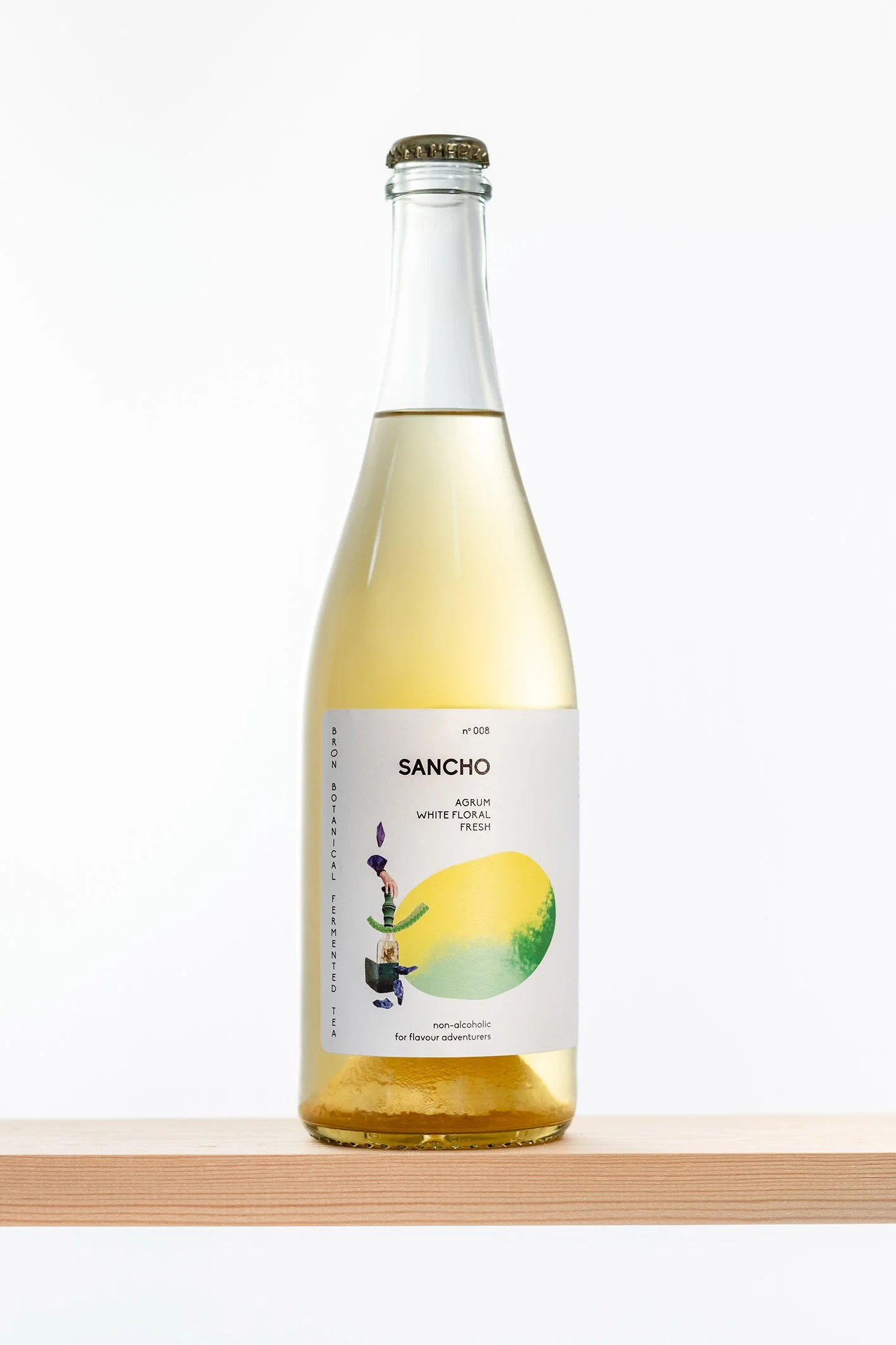 Bergfles uit een glazen fles met een witte wijnige inhoud, label met een citroenillustratie en tekst over thee en smaak, op een houten plank.