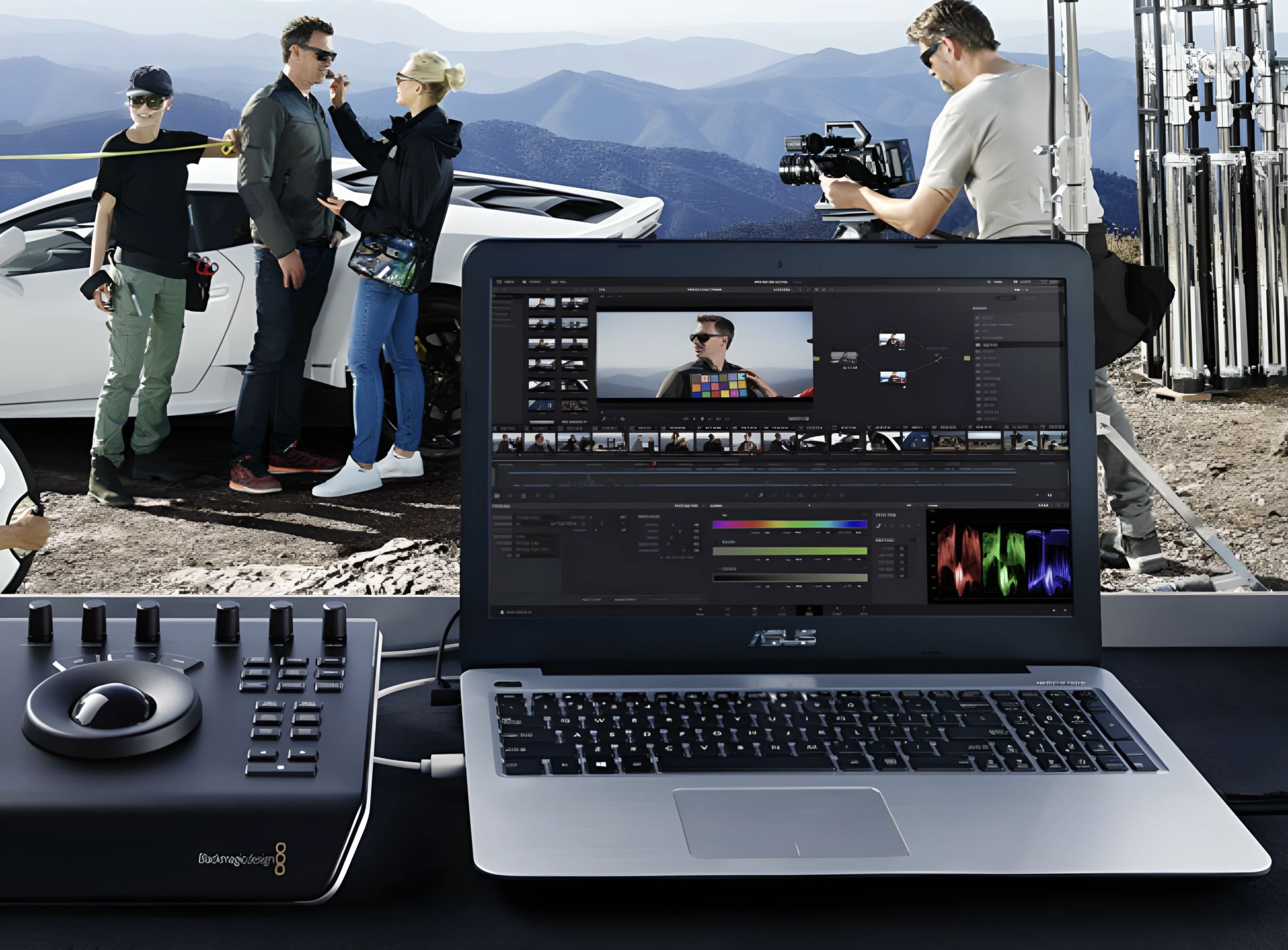 Video production crew filming a scene with a white sports car against mountain scenery, with a computer and audio equipment in the foreground.
