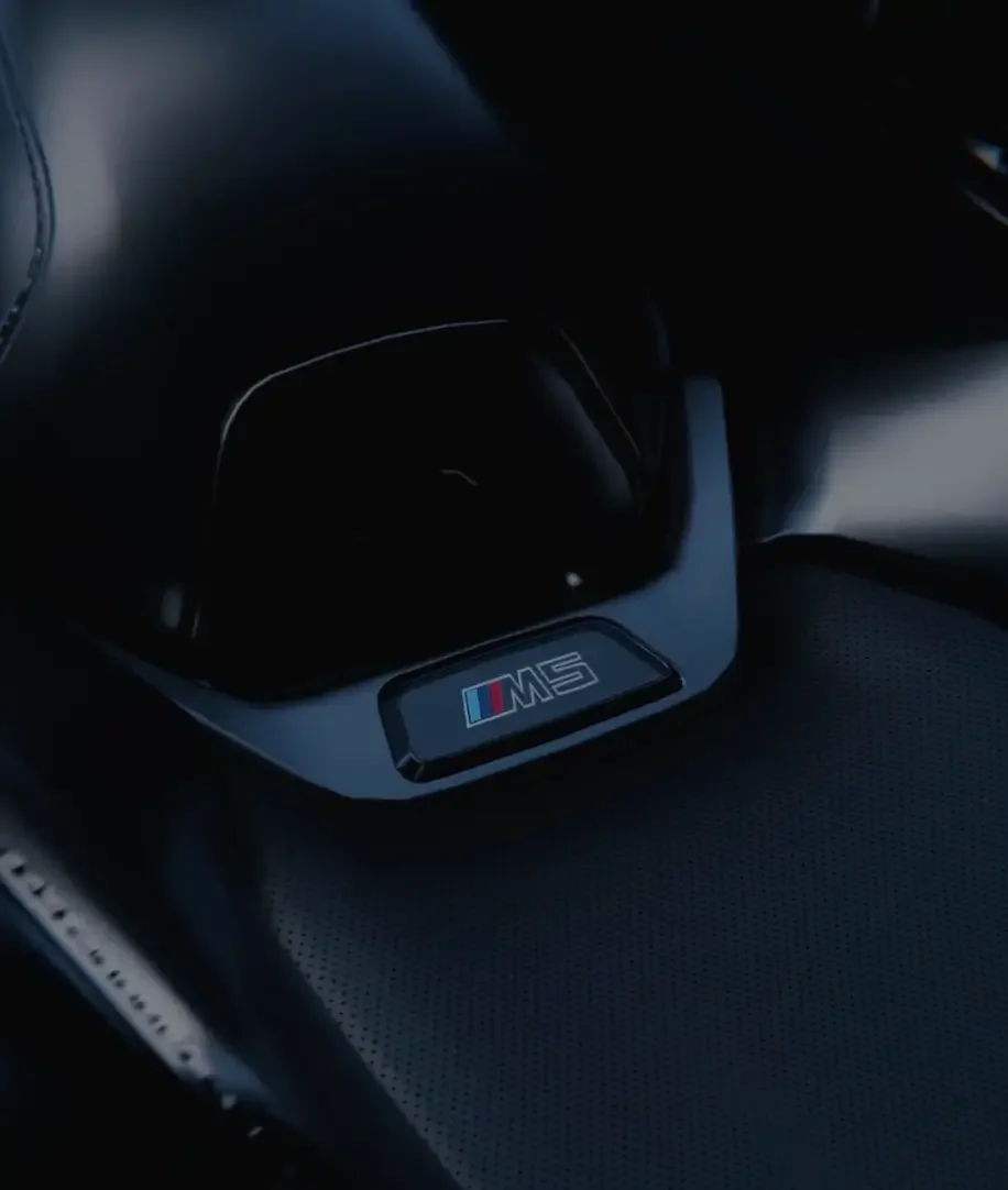 Automotive Interior Visualisierung: Fotorealistisches Macro-Rendering des BMW M5 Logos, das in perforiertes schwarzes Leder eingelassen ist.