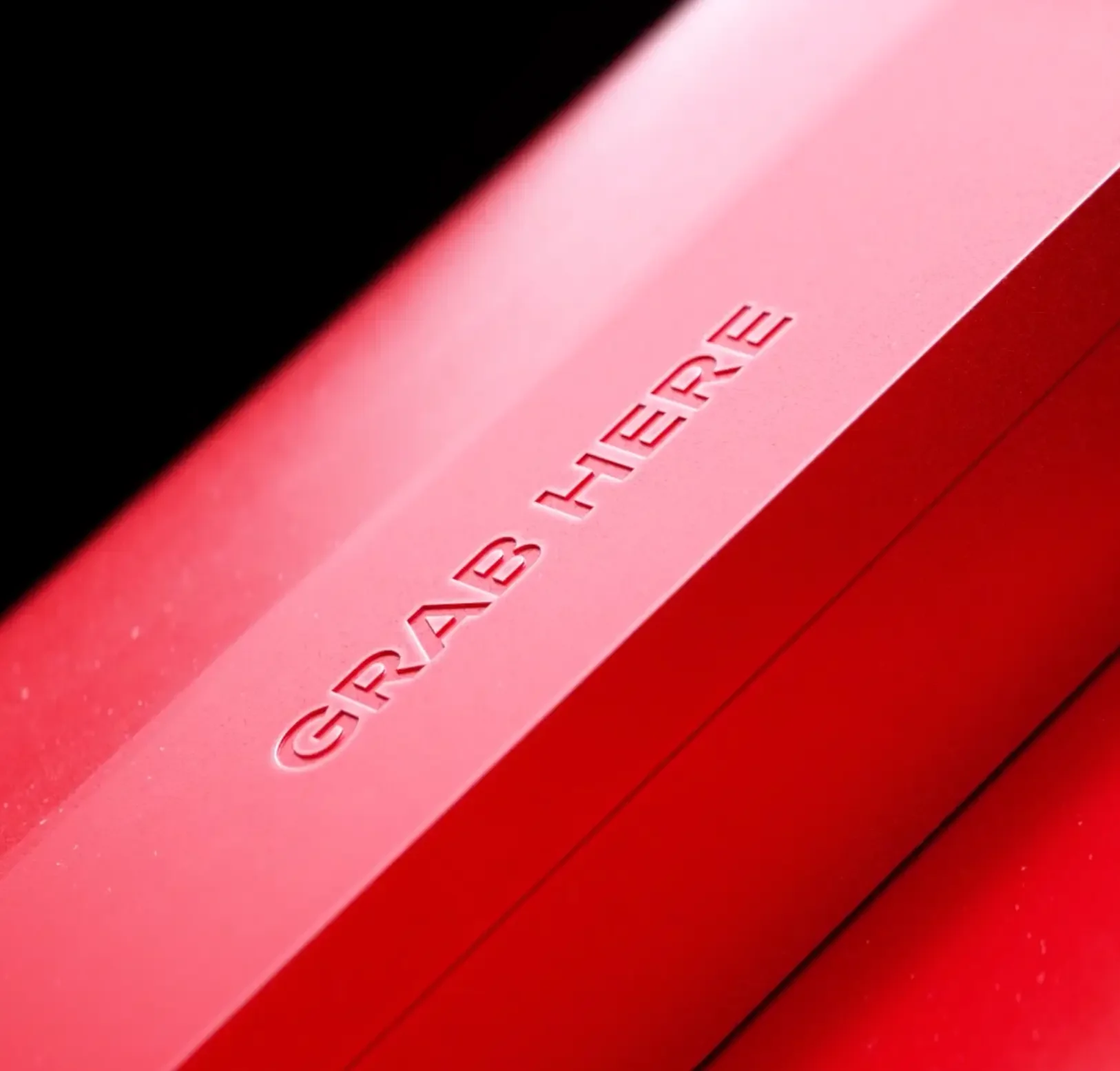 High-End Detail-Rendering: Fotorealistische Nahaufnahme einer roten matten Oberfläche mit der eingeprägten Aufschrift "GRAB HERE".