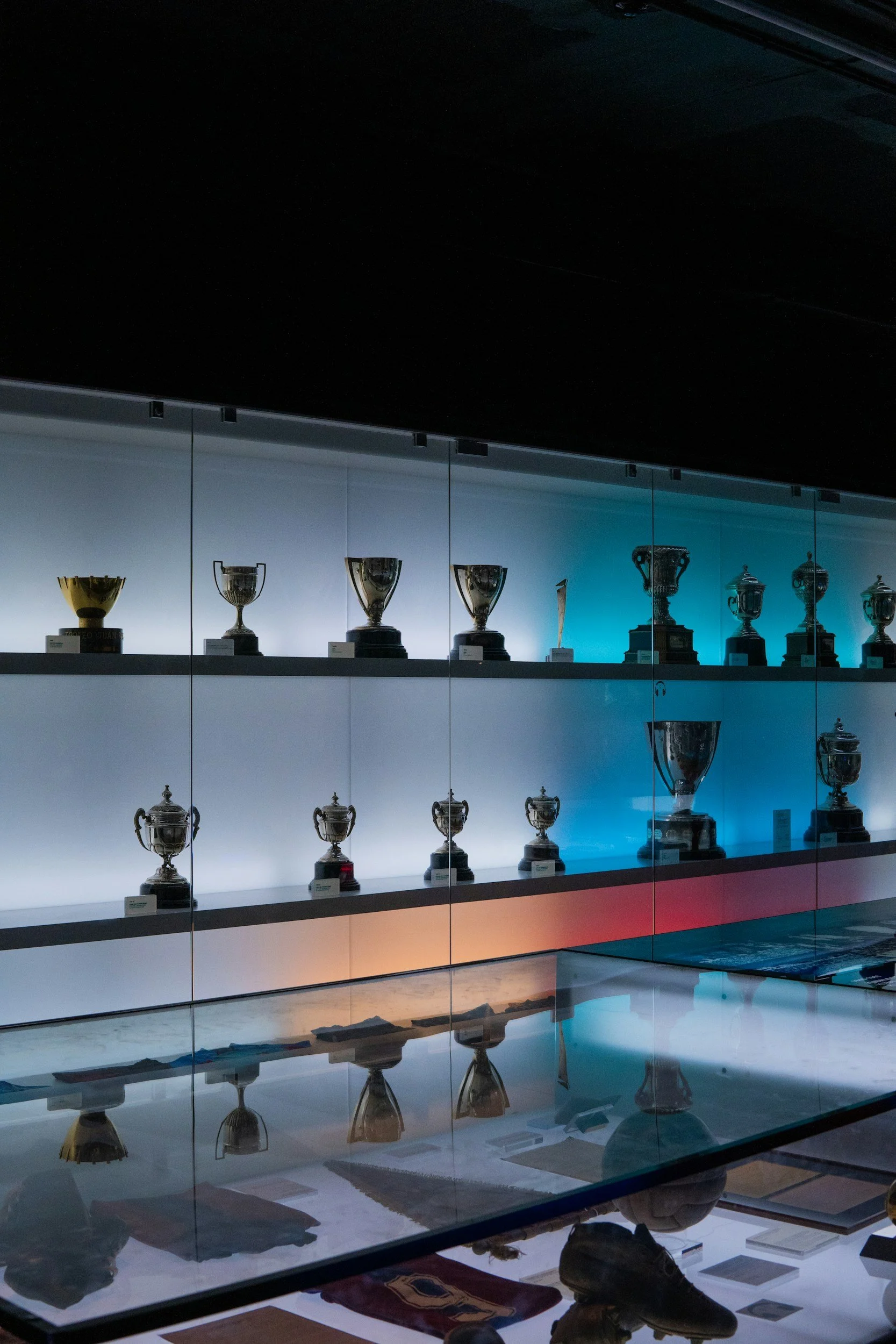 Display of trophies in a glass case, illuminated with multicolored lighting.