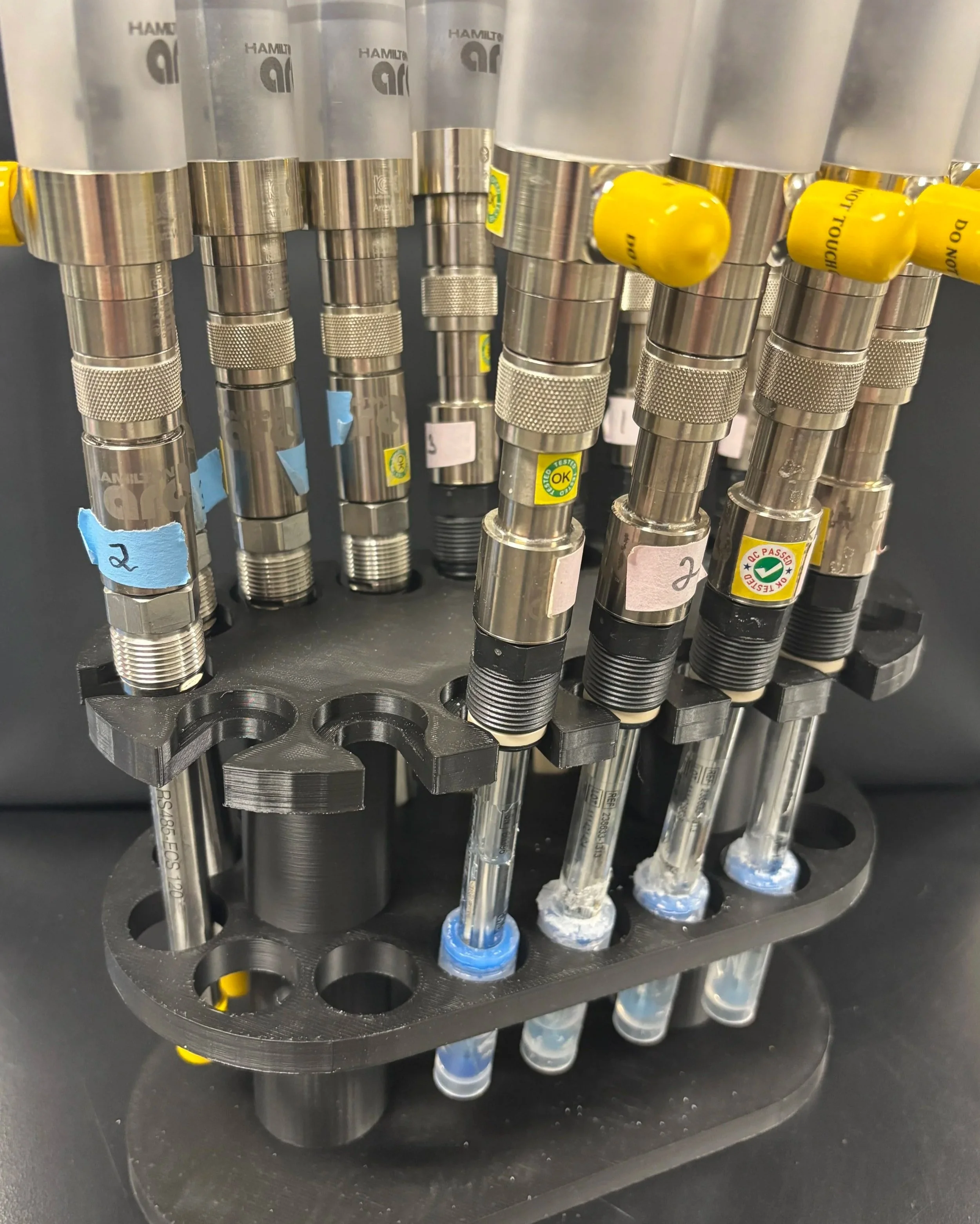 Collection of fermentation probes with metal fittings and pH caps in a black 3D printed PETG rack.