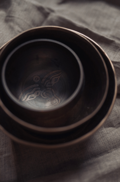Close-up of stacked black ceramic cups on a gray fabric surface.