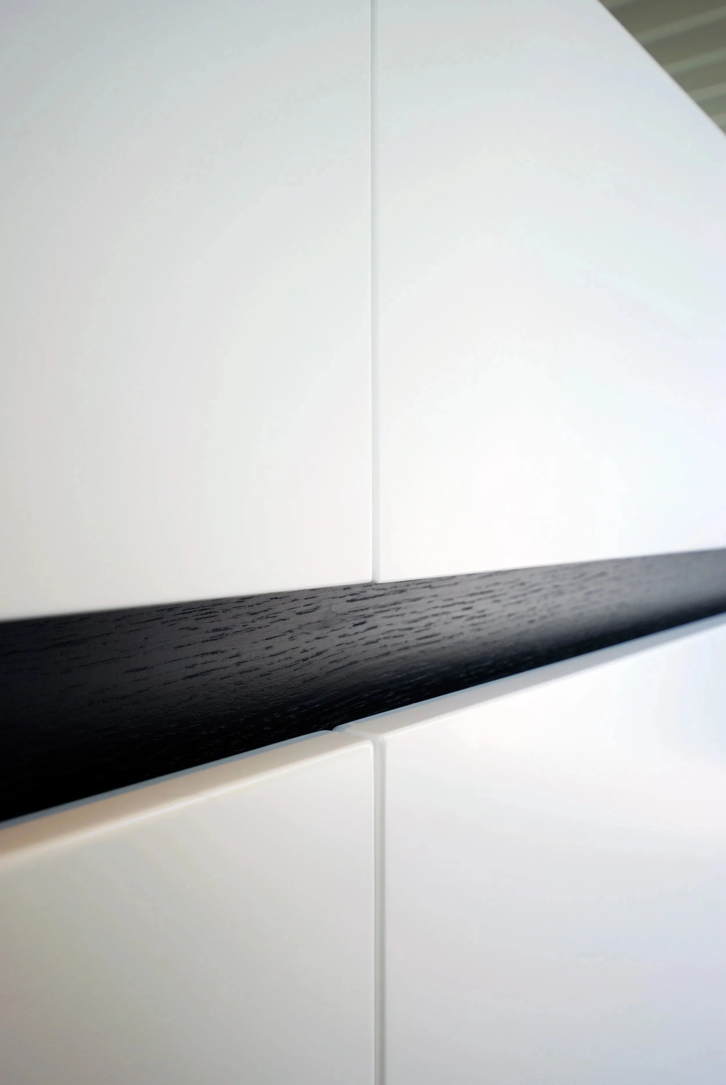 Close-up van witte kasten met een zwarte houten strip ertussen.