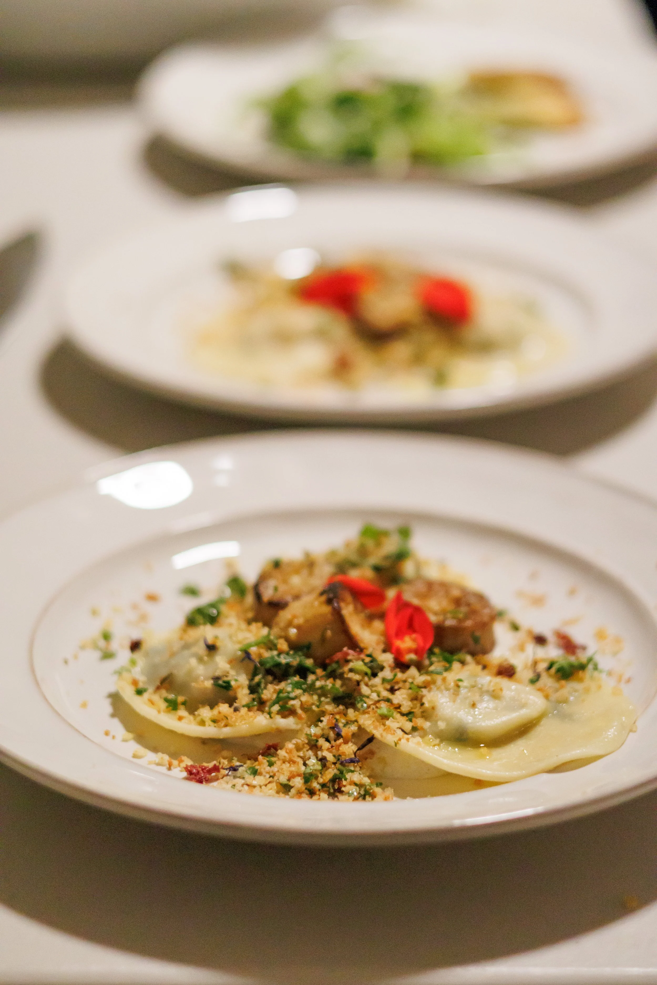 Close-up of a plate of seafood pasta with garnishes, served in a white bowl.
