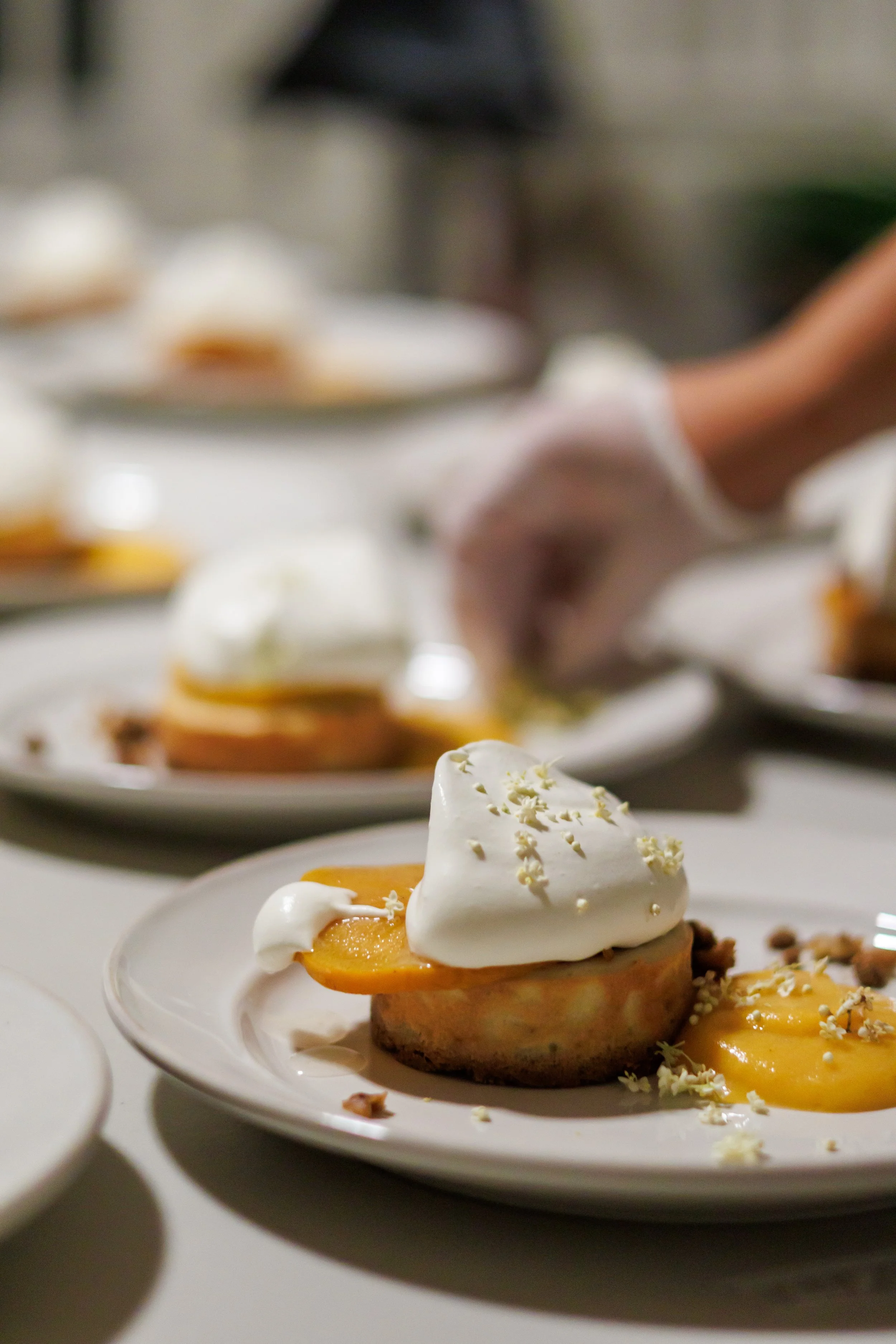 Plate with a dessert featuring a halved peach, whipped cream, and white chocolate shavings.