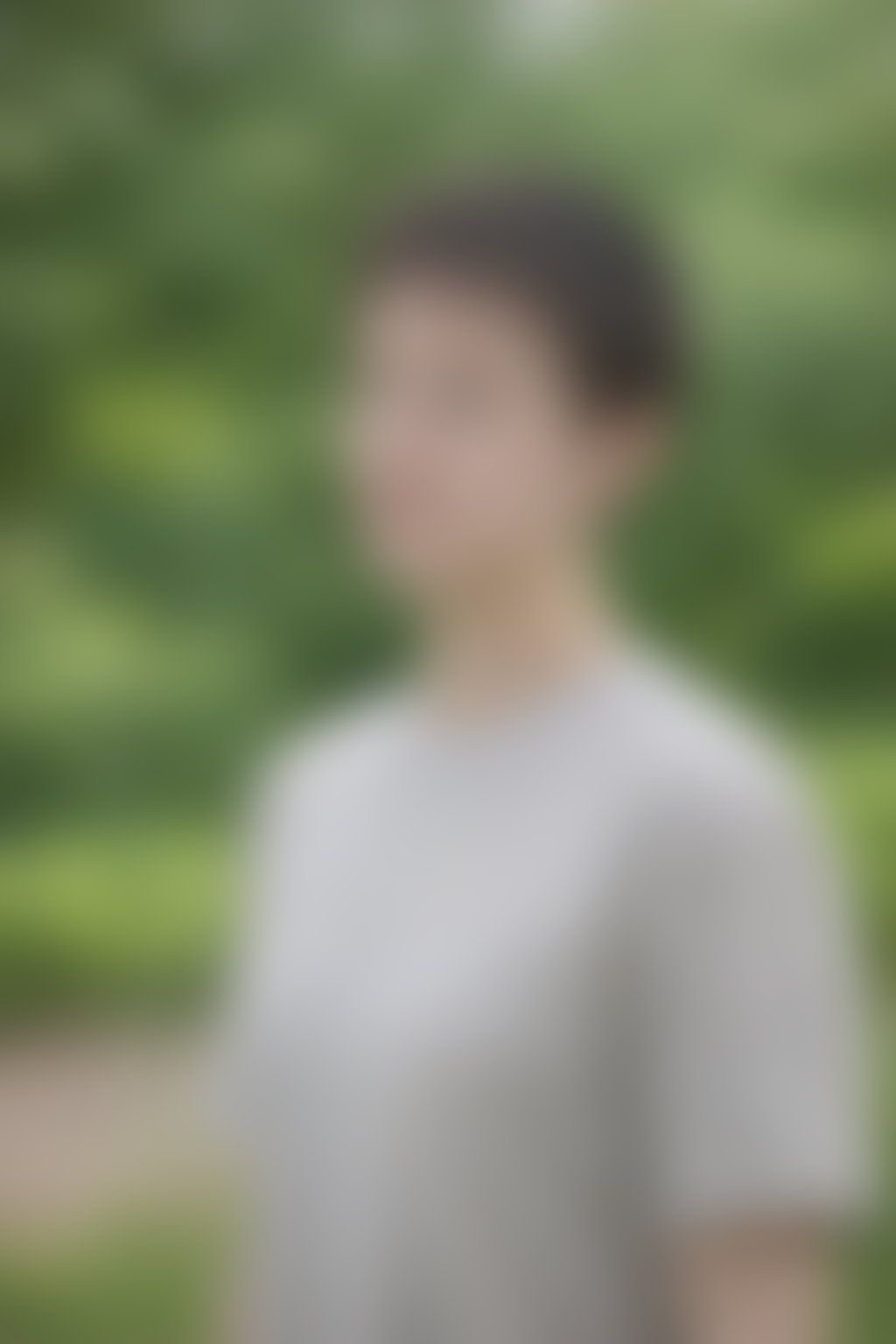 Ein unscharfes Porträt eines Menschen vor einem grünen, natürlichen Hintergrund.