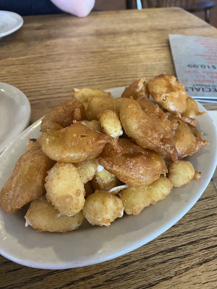 Fried battered shrimp on a white oval plate on a wooden table.
