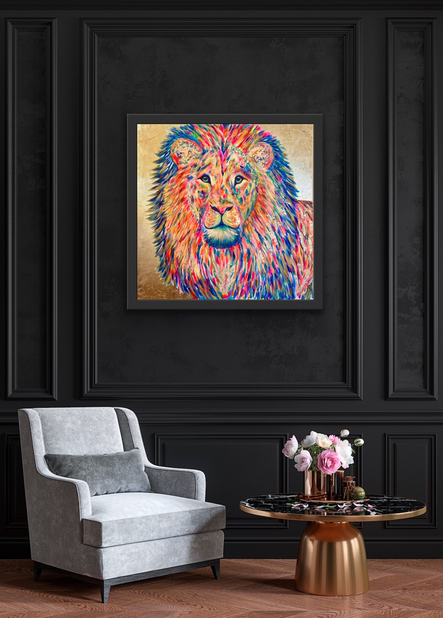A colorful painting of a lion with a vibrant mane hanging on a black wall in a modern living room. There's a gray armchair with a dark gray pillow and a round black and gold table with pink flowers in a copper vase in front of the wall.