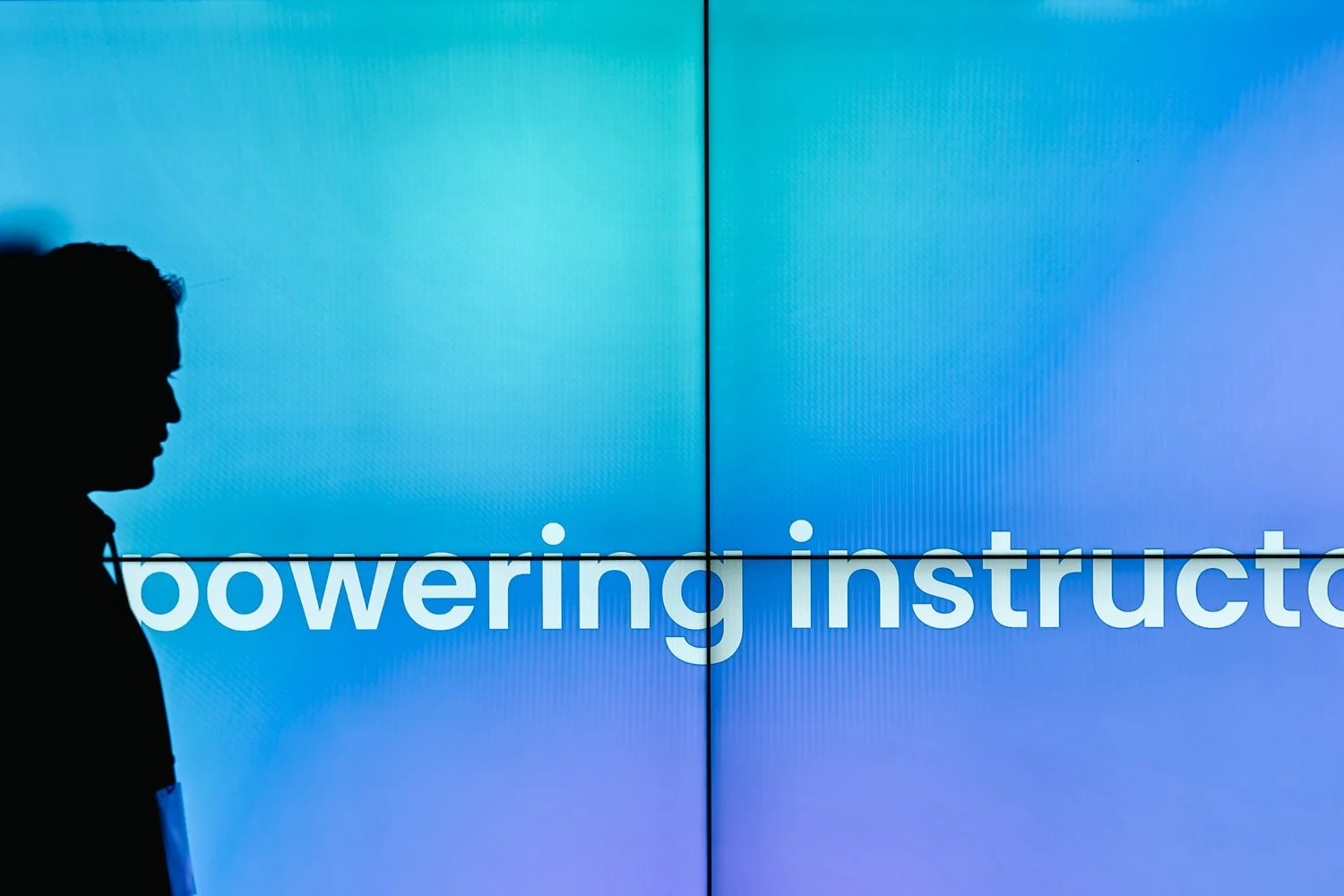 Silhouette of a person in front of a blue screen with the words "powering instructo" partially visible.