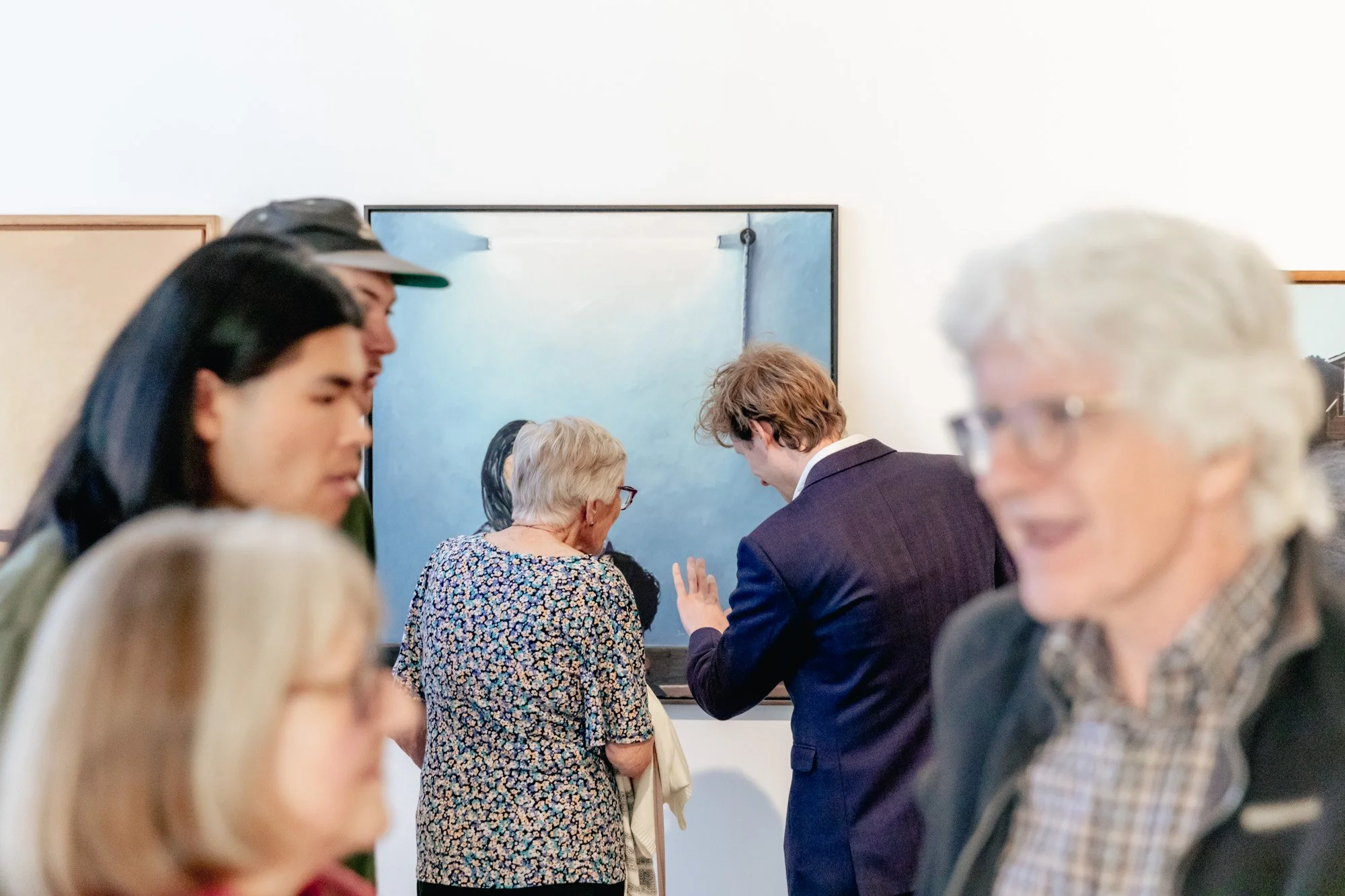 People at an art gallery looking at and discussing a painting.