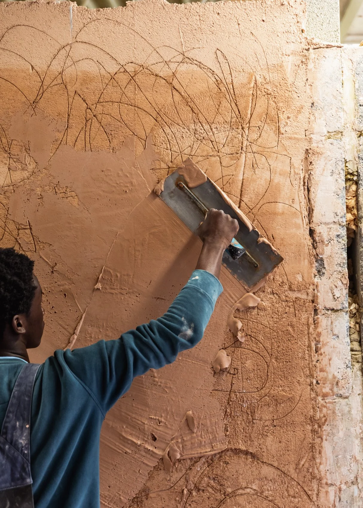 Person smoothing a brick wall with a trowel.