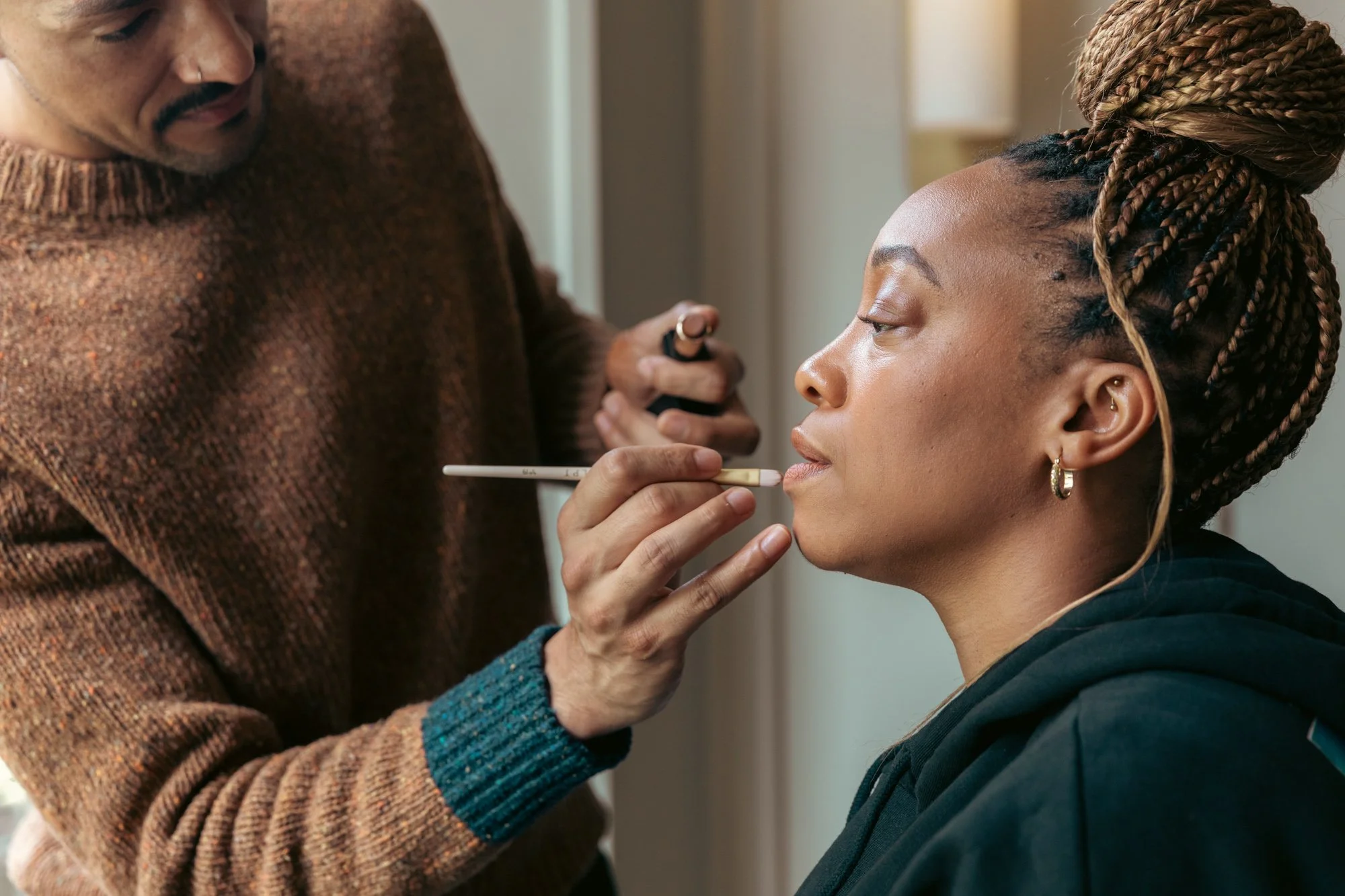 Makeup artist applying makeup to woman with braided hair