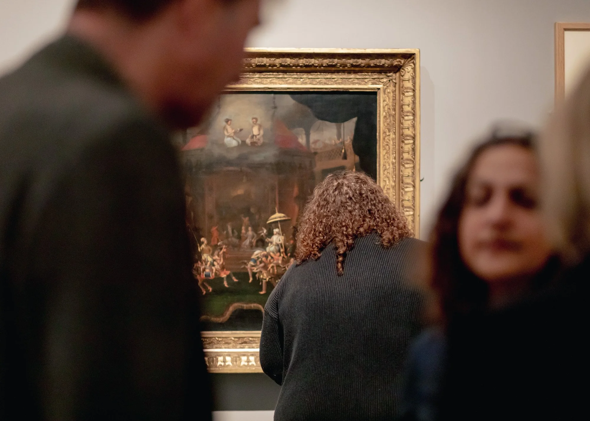 People viewing a classic painting in an art gallery.