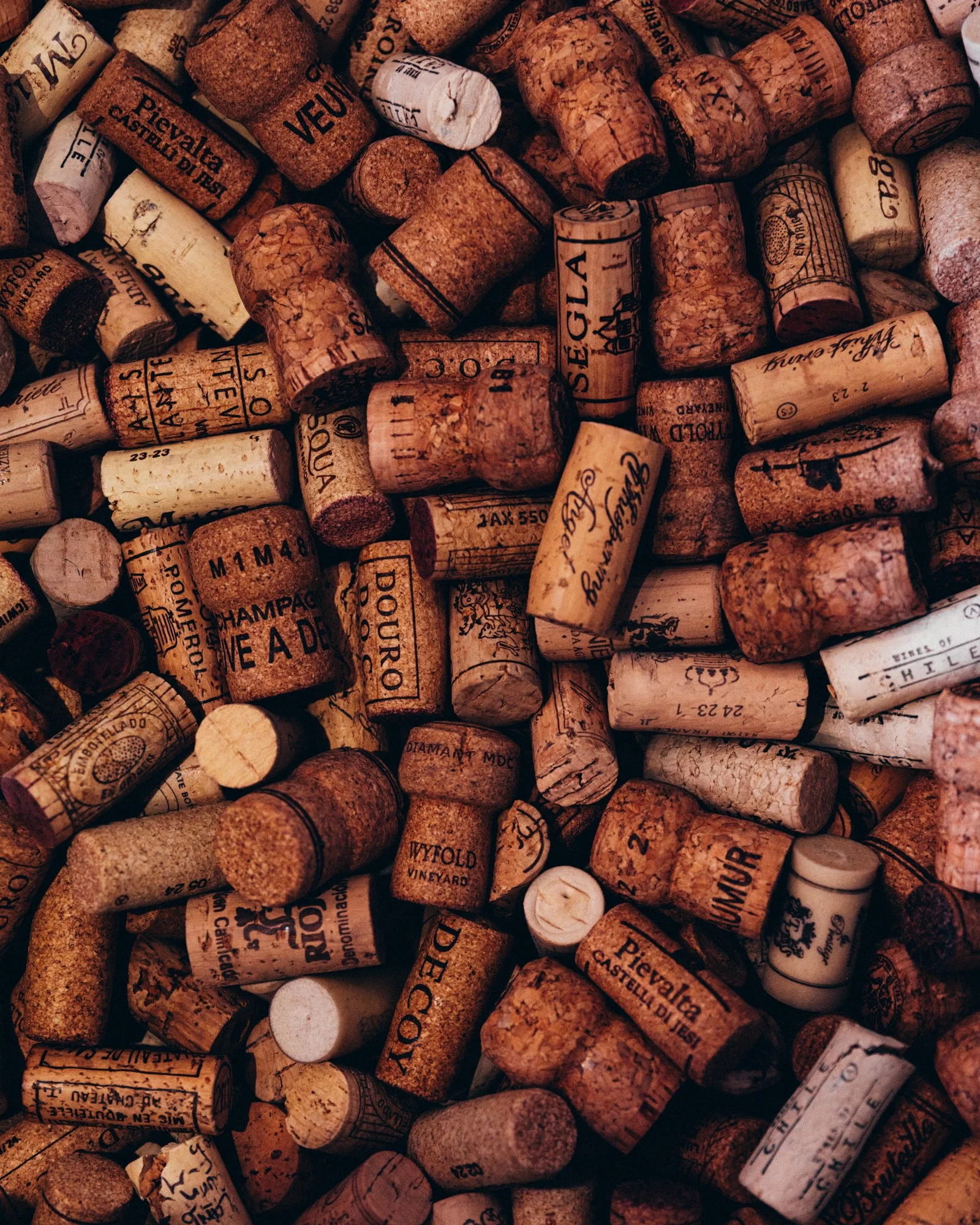 An assortment of wine corks, some with visible logos, text, and patterns, in various shades of brown and beige.