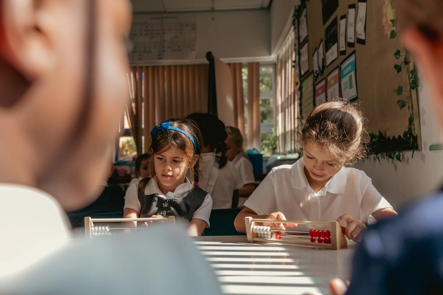 Young children playing with abacuses in a classroom.