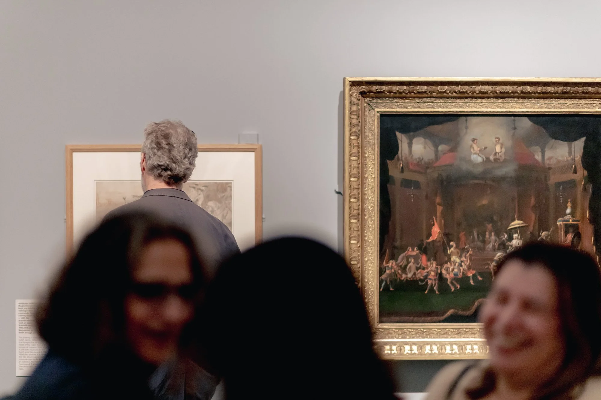 People viewing artwork in a gallery, with two artworks on the wall.