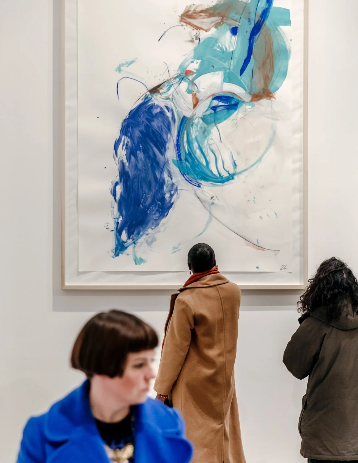 People viewing an abstract painting with large blue and light blue brushstrokes in an art gallery.