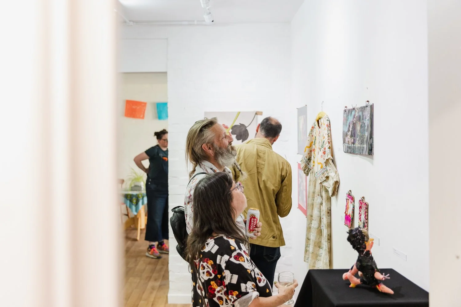 People viewing artwork and crafts at an art gallery.