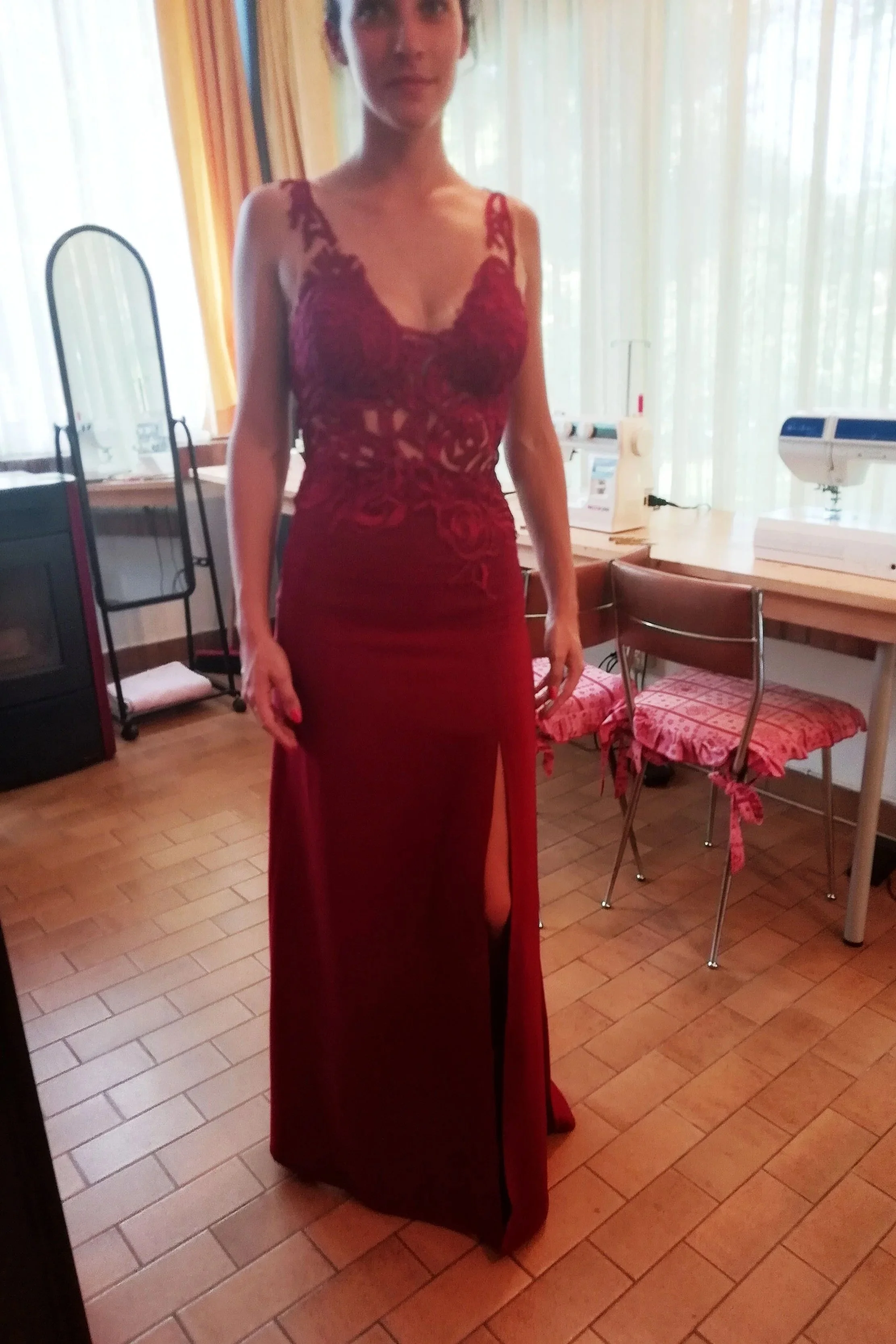 Bespoke floor-length red evening gown for a wedding guest, featuring a sheer bodice created with individual lace pieces hand-sewn onto nude mesh and a thigh-high leg slit, hand-crafted in the Elena Milani studio