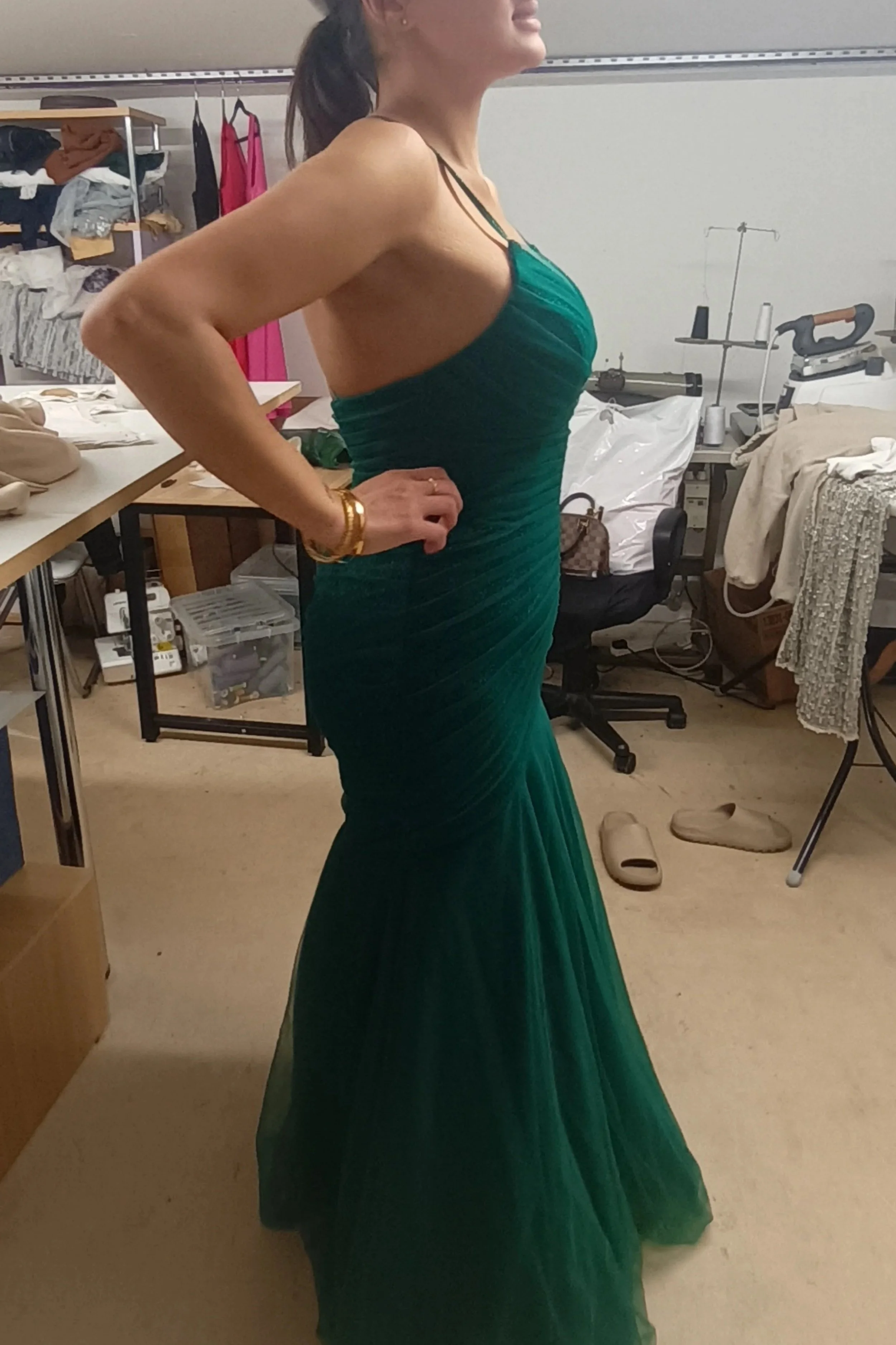 Wedding guest posing in a bespoke floor-length emerald green gown featuring a complex hand-pleated bodice and flared tulle skirt, custom-made in Elena Milani's Burnham-on-Crouch studio