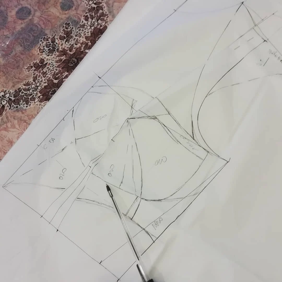 Technical drawing with measurements and sketches, on white paper, with a pen pointing at the drawing.