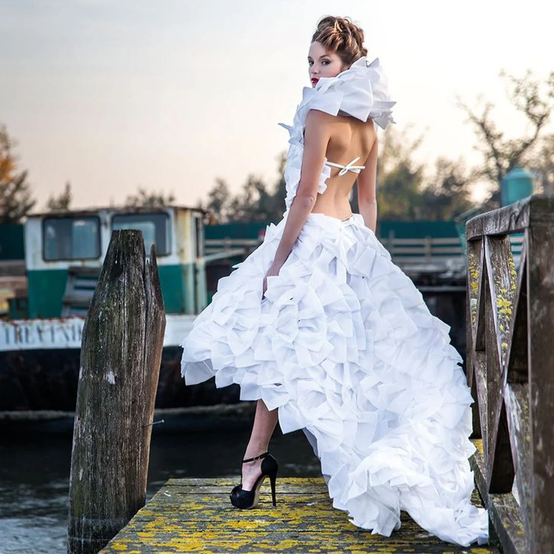 "Bespoke high-low couture bridal gown by Elena Milani. Featuring hundreds of hand-sewn fans crafted with Venetian precision. Masterfully engineered in Essex.