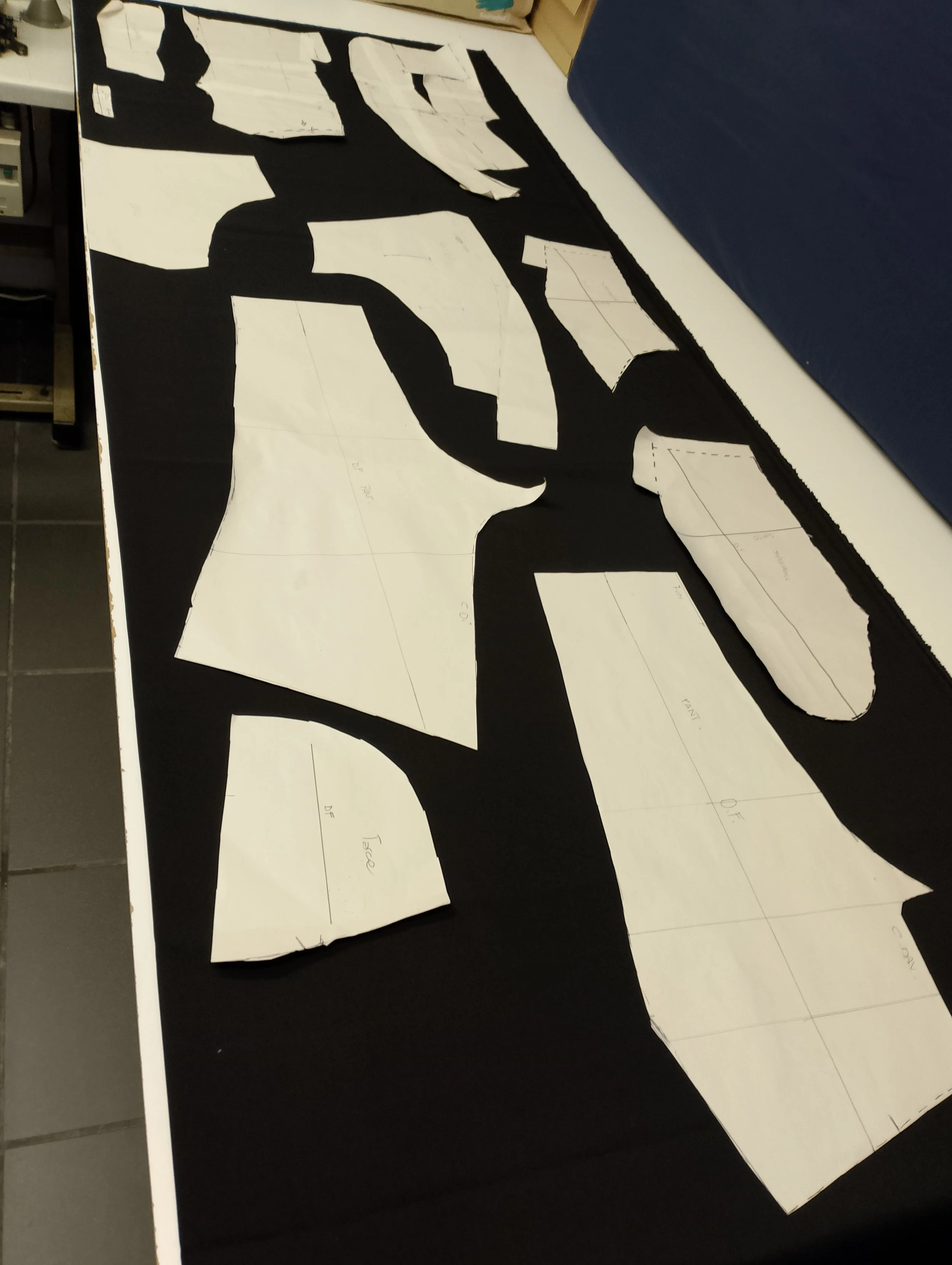 Cut-out paper pattern pieces for a fabric project with black and white colors on a table.