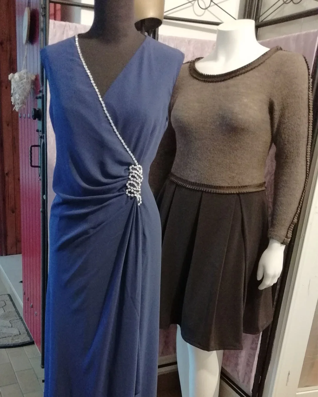 Bespoke studio display in Burnham-on-Crouch featuring a floor-length blue evening gown with crystal-embellished draping and a sophisticated brown wool daywear set with a pleated skirt, showcasing 16 years of Venetian tailoring expertise.