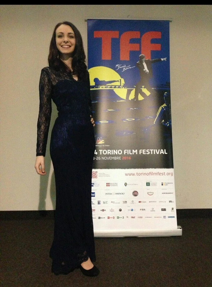 Italian actress on the red carpet at the 34th Turin Film Festival wearing a bespoke floor-length blue lace gown with intricate detailing, hand-crafted by Elena Milani using italian tailoring techniques
