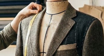 Close-up of the master tailor taking precise lapel and chest measurements on a men's bespoke tweed jacket, showcasing the detailed texture of the hand-drafted garment in the Elena Milani studio