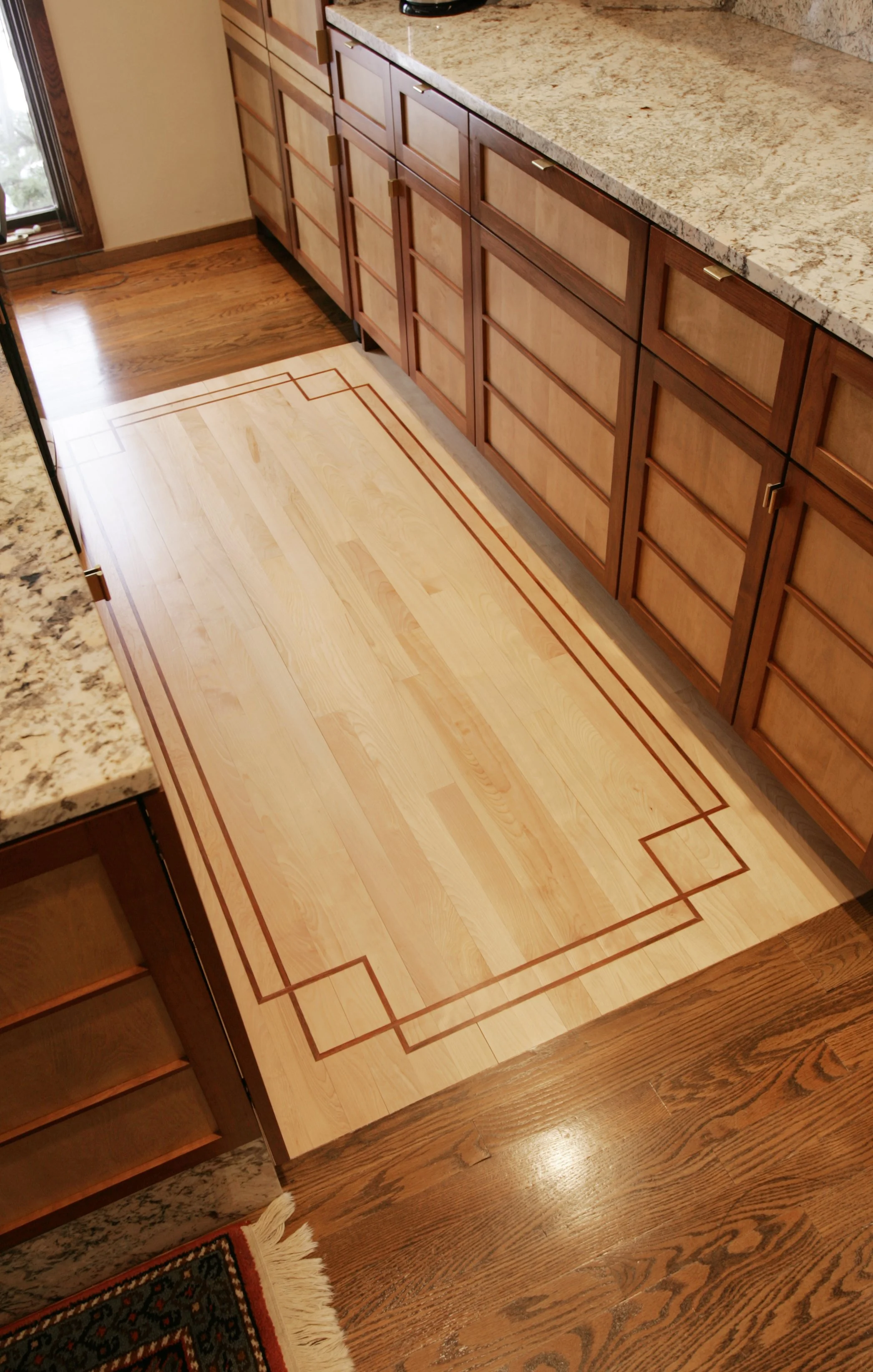 Kitchen with granite countertops, wooden cabinets, hardwood floor, and a decorative wooden floor inlay.