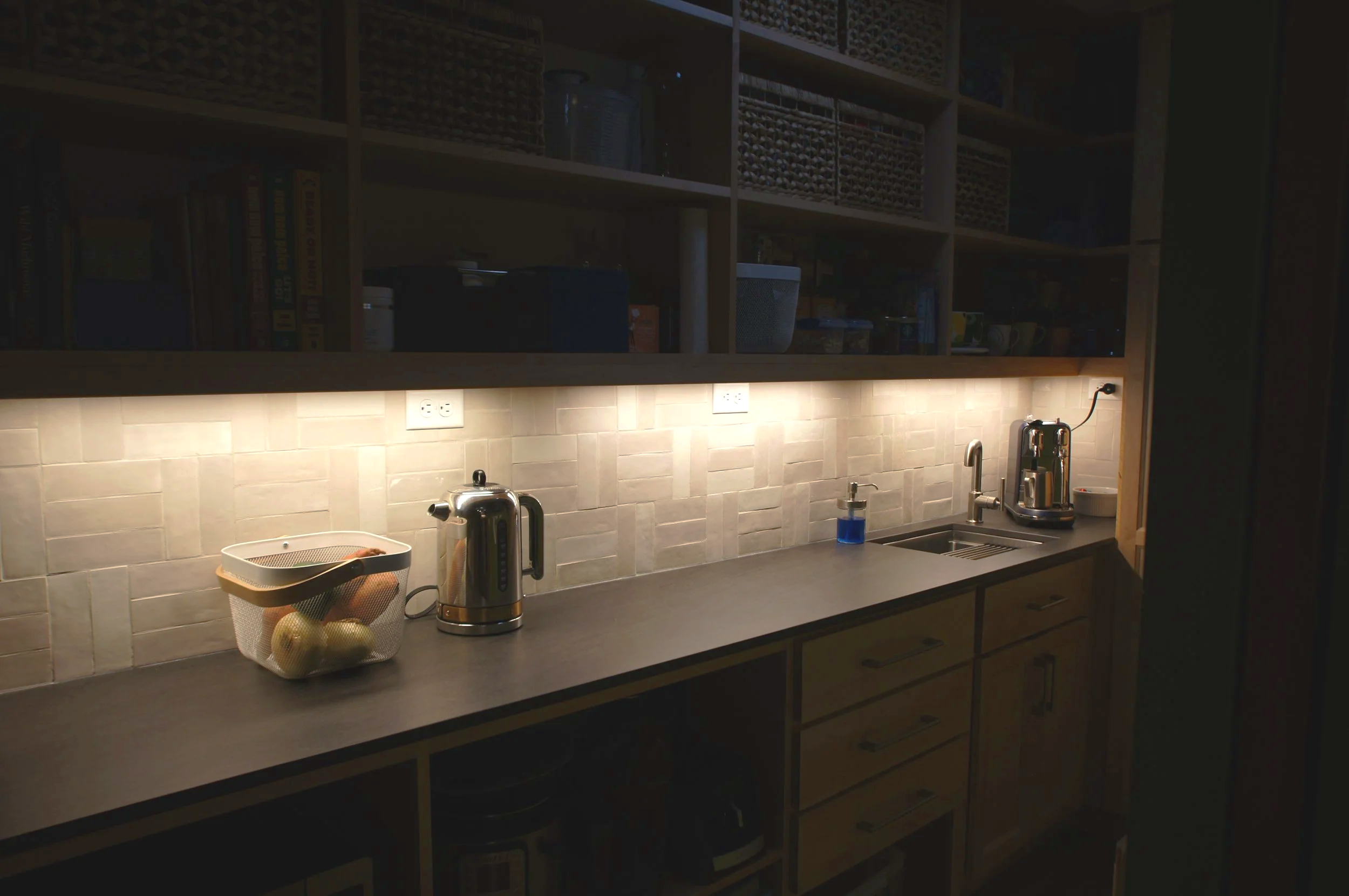 Undercabinet lighting in this pantry elevates the space from a utilitarian closet to a cozy nook for coffee and tea.