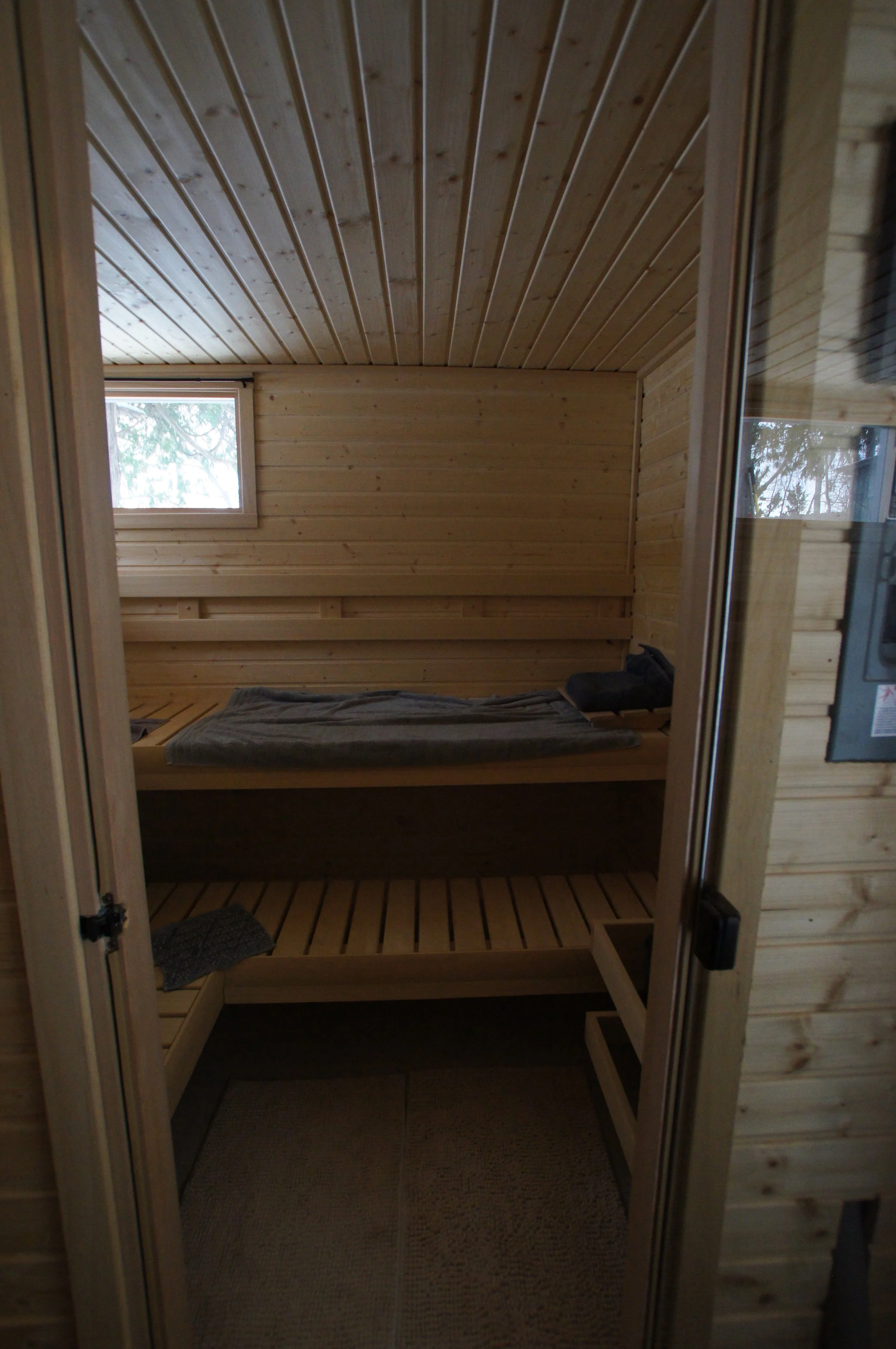 Inside a small wooden sauna with a bench and a window.