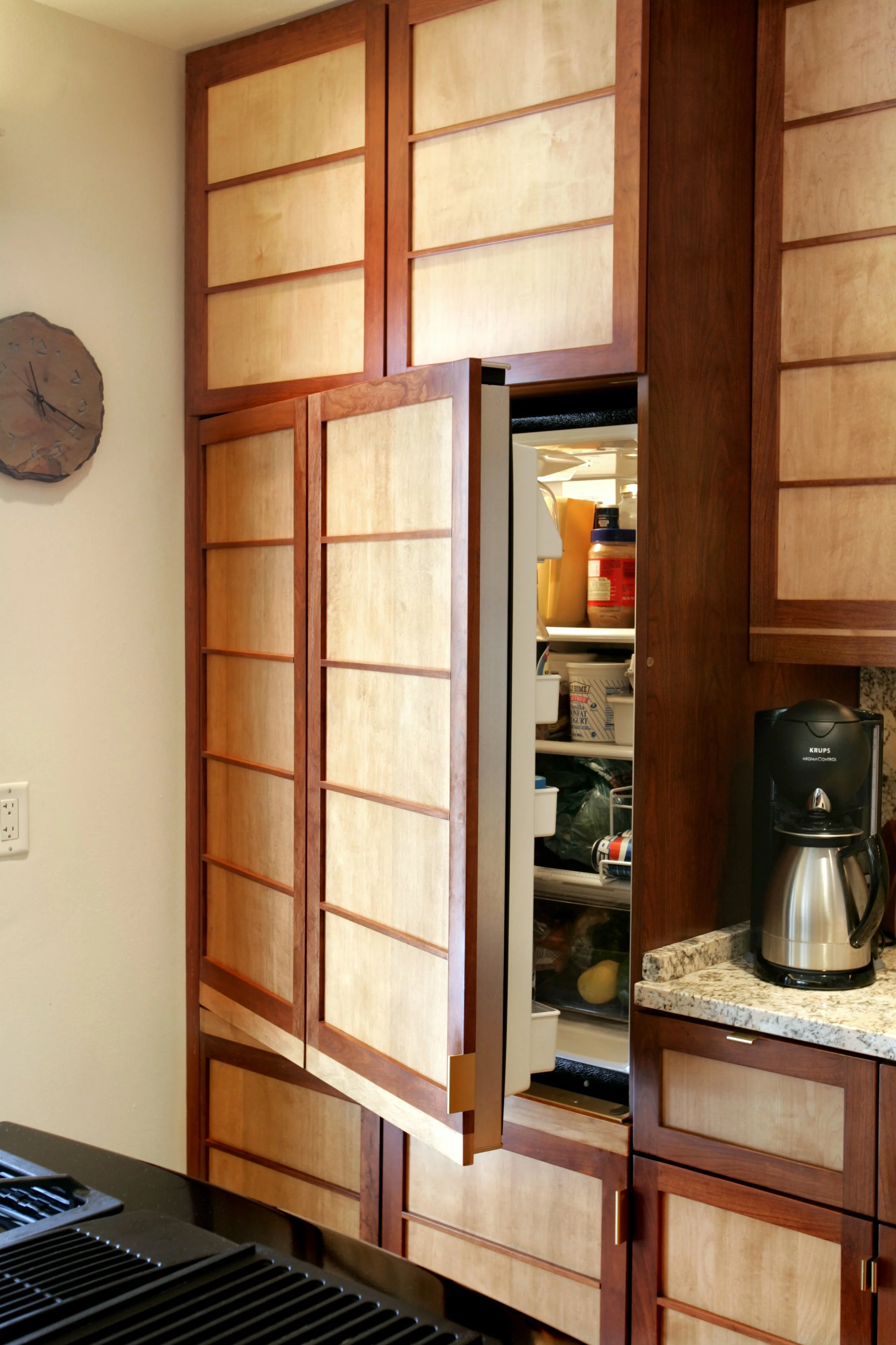 Open refrigerator door in a kitchen with wooden cabinets and a coffee maker on the countertop.