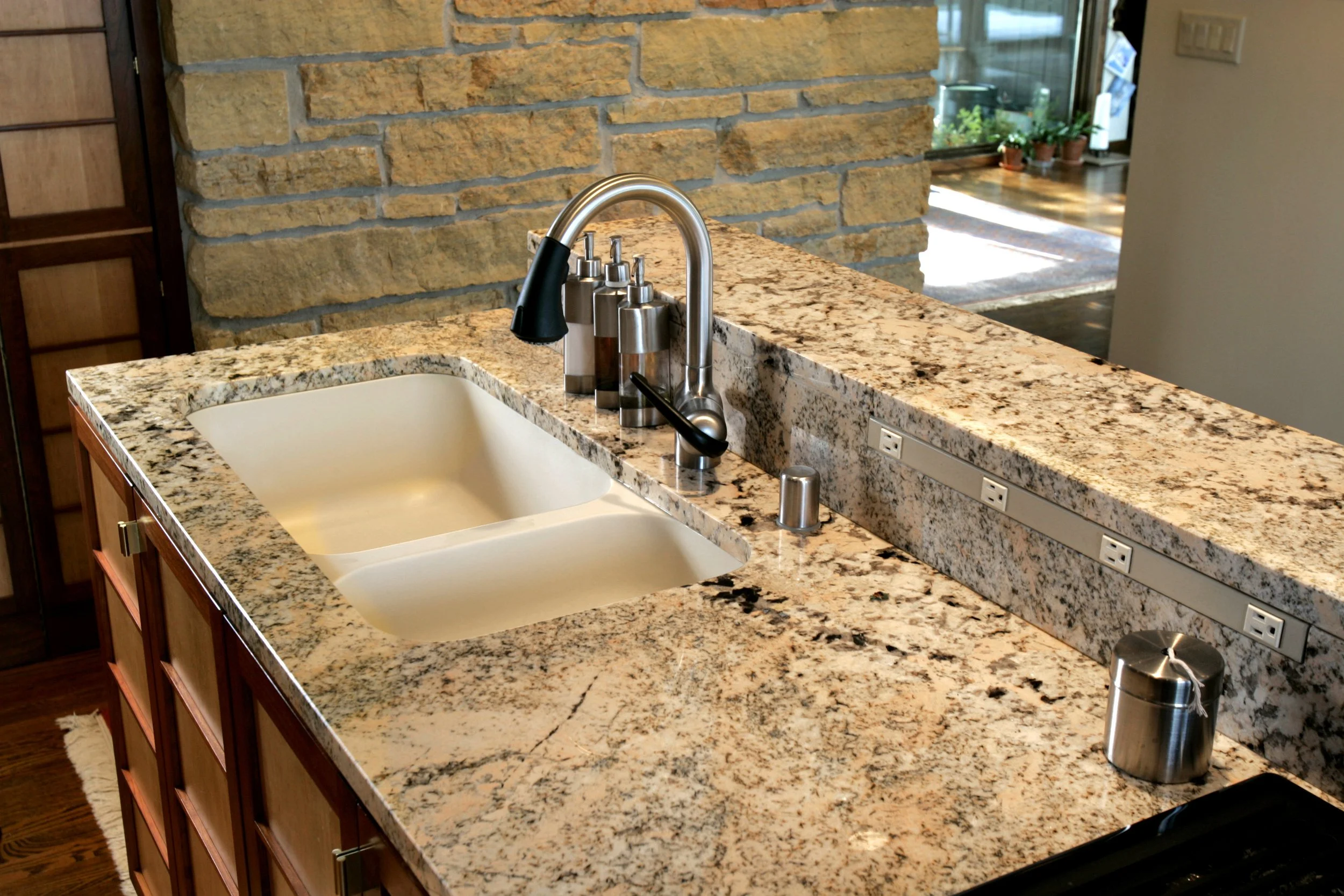 Kitchen sink with granite countertop, stainless steel faucet, and soap dispensers.