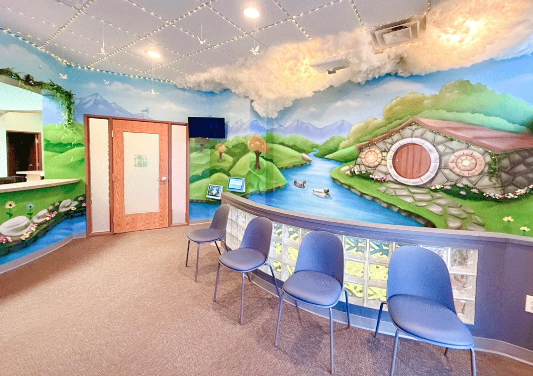 waiting area with whimsical mural of cottage and river and greenery