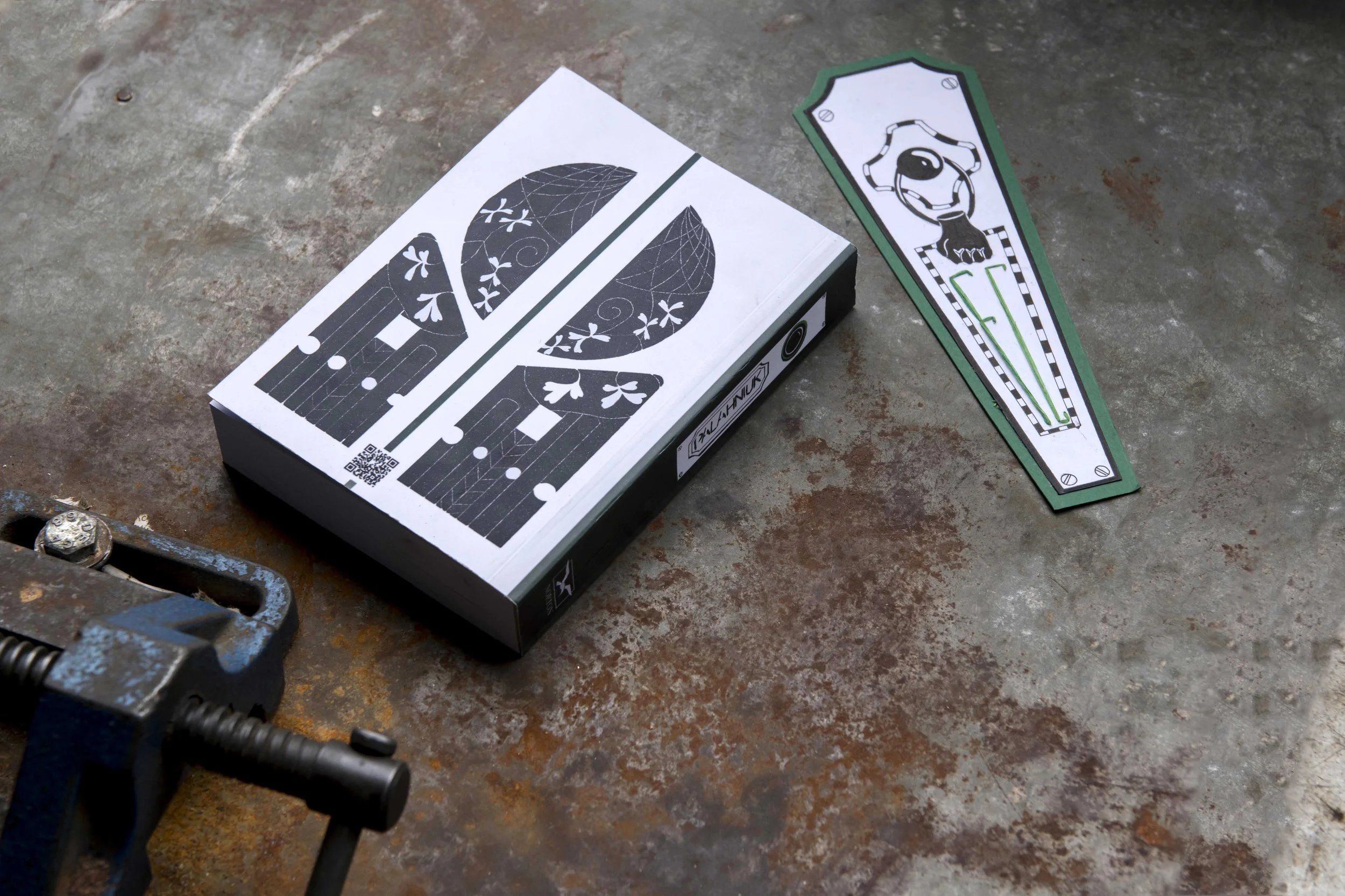 A pair of tree-shaped stickers, a box with a tree-shaped design on the cover, and a clamp on a rusted metal surface. LEA SABAN, DOĞU & ERİNÇ PORTFOLYO HAZIRLIK ATÖLYESİ VE EĞİTİM DANIŞMANLIĞI