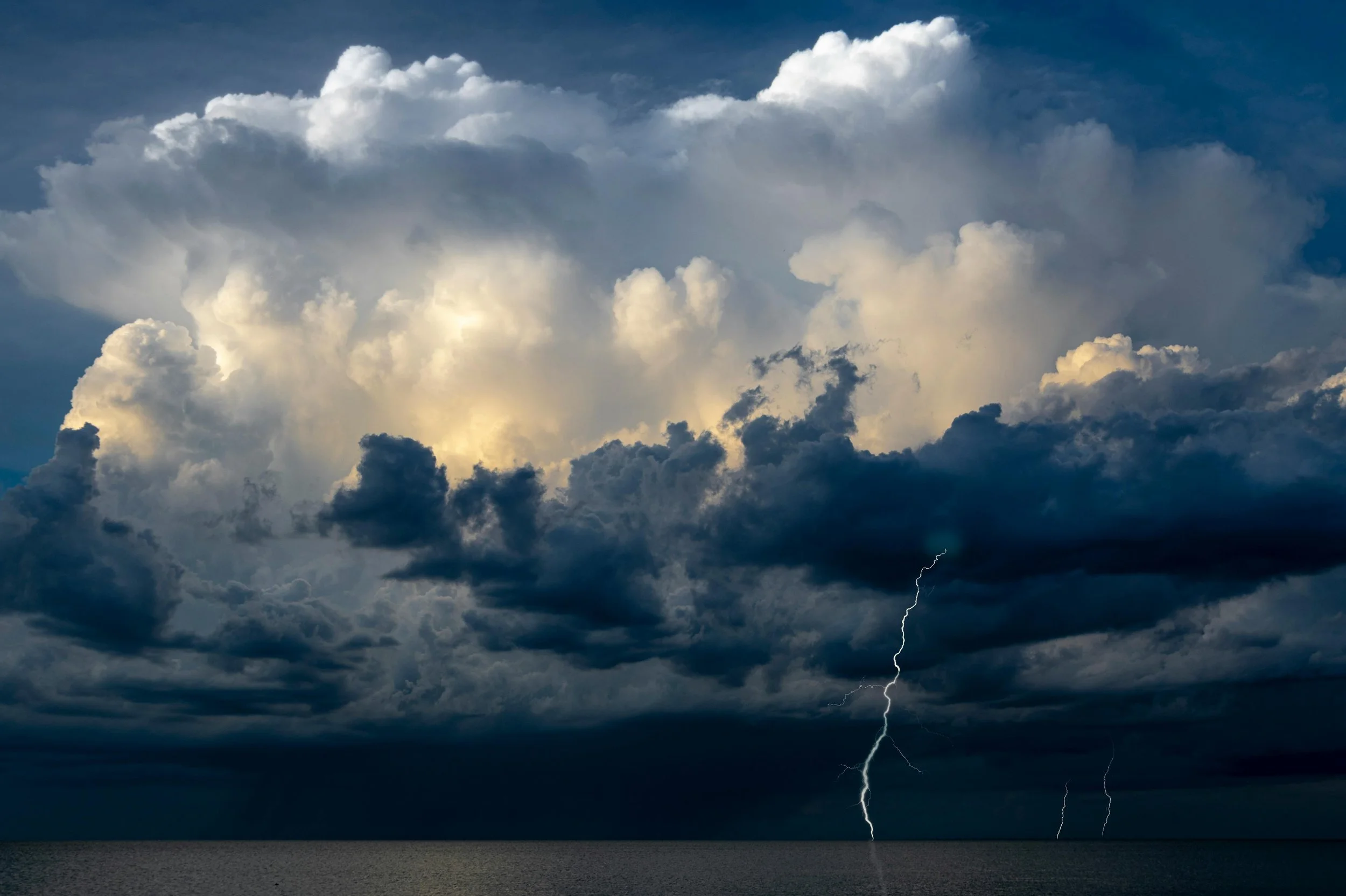 Dark storm clouds over the ocean with lightning strikes.
